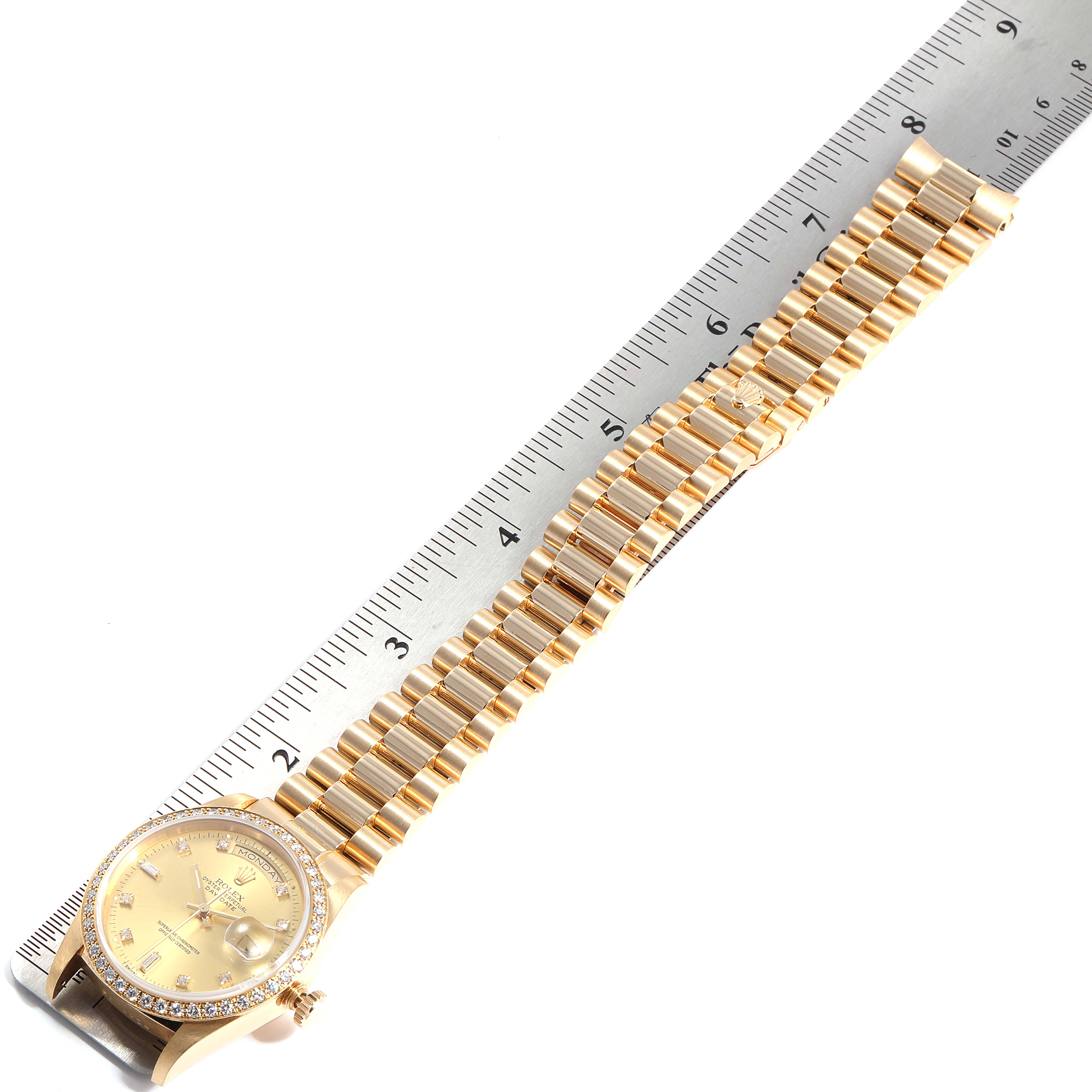 The image shows a Rolex President 18348 Men
s Yellow Gold Champagne Dial 18348 Men
s Yellow Gold Champagne Dial model watch laid flat beside a ruler, displaying the watch face and entire bracelet.