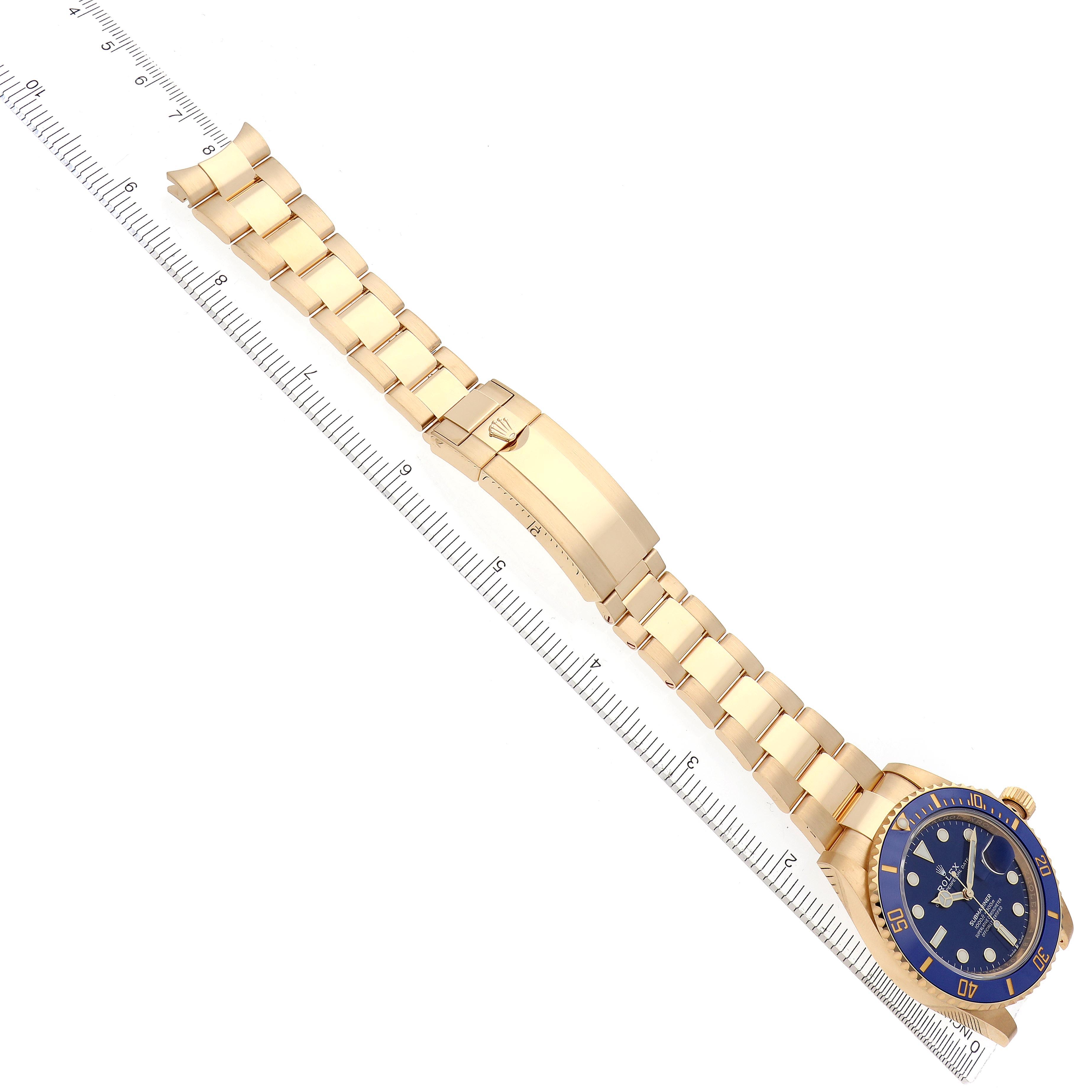 The Rolex Submariner 126618LB Men's Yellow Gold Blue Dial 126618LB Men's Yellow Gold Blue Dial watch is shown from a top-down angle, highlighting its bracelet, clasp, and bezel next to a ruler.
