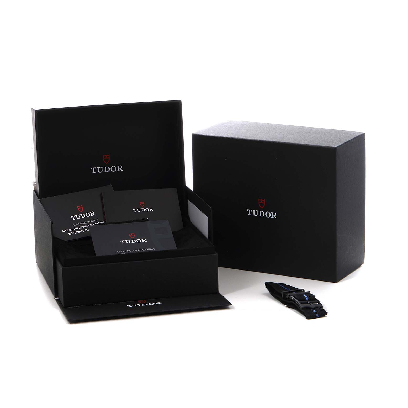 The image shows the Tudor Heritage Black Bay 79210 Men's Ceramic Blue Dial packaging with warranty cards and a strap at an angled view.