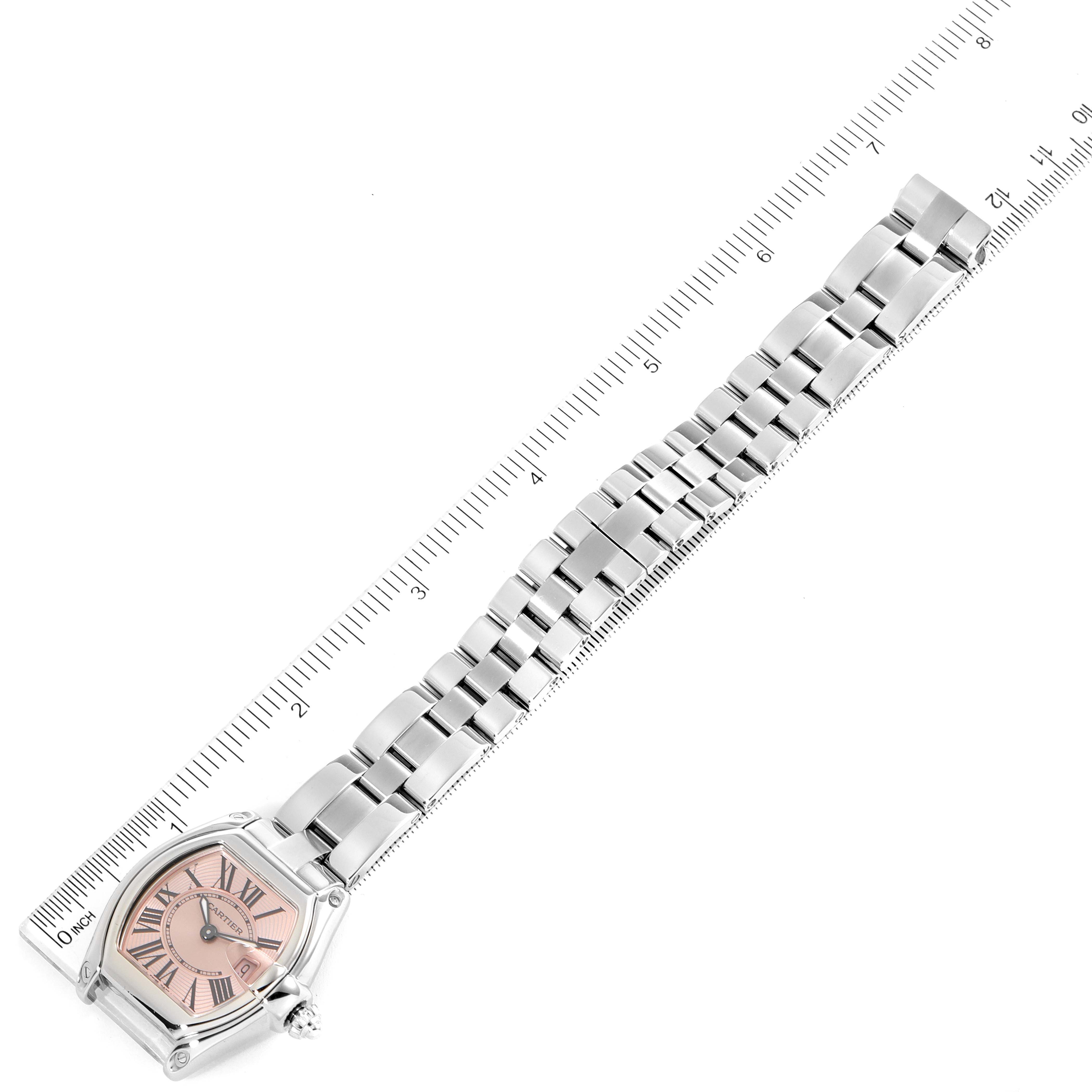 The Cartier Roadster W62017V3 Women's Stainless Steel Pink Dial W62017V3 Women's Stainless Steel Pink Dial watch is shown from a top-down angle, with its wristband fully extended next to a ruler for measurement.