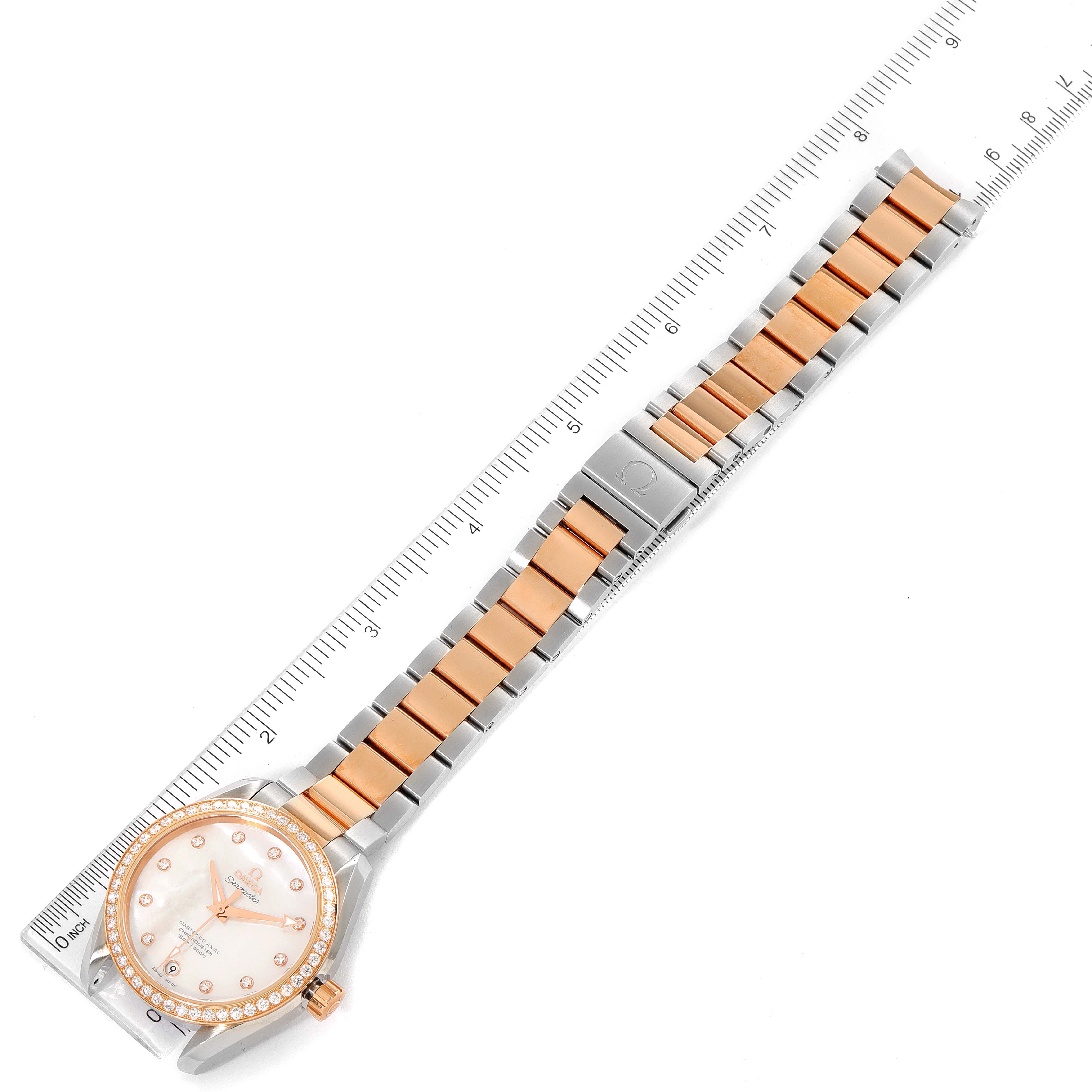 The Omega 231.25.39.21.55.001 Women's Steel and Gold (two tone) Mother of Pearl Dial 231.25.39.21.55.001 Women's Steel and Gold (two tone) Mother of Pearl Dial Aqua Terra Steel Rose Gold Diamond Ladies Watch 231.25.39.21.55.001 is shown laying flat with a ruler alongside it.