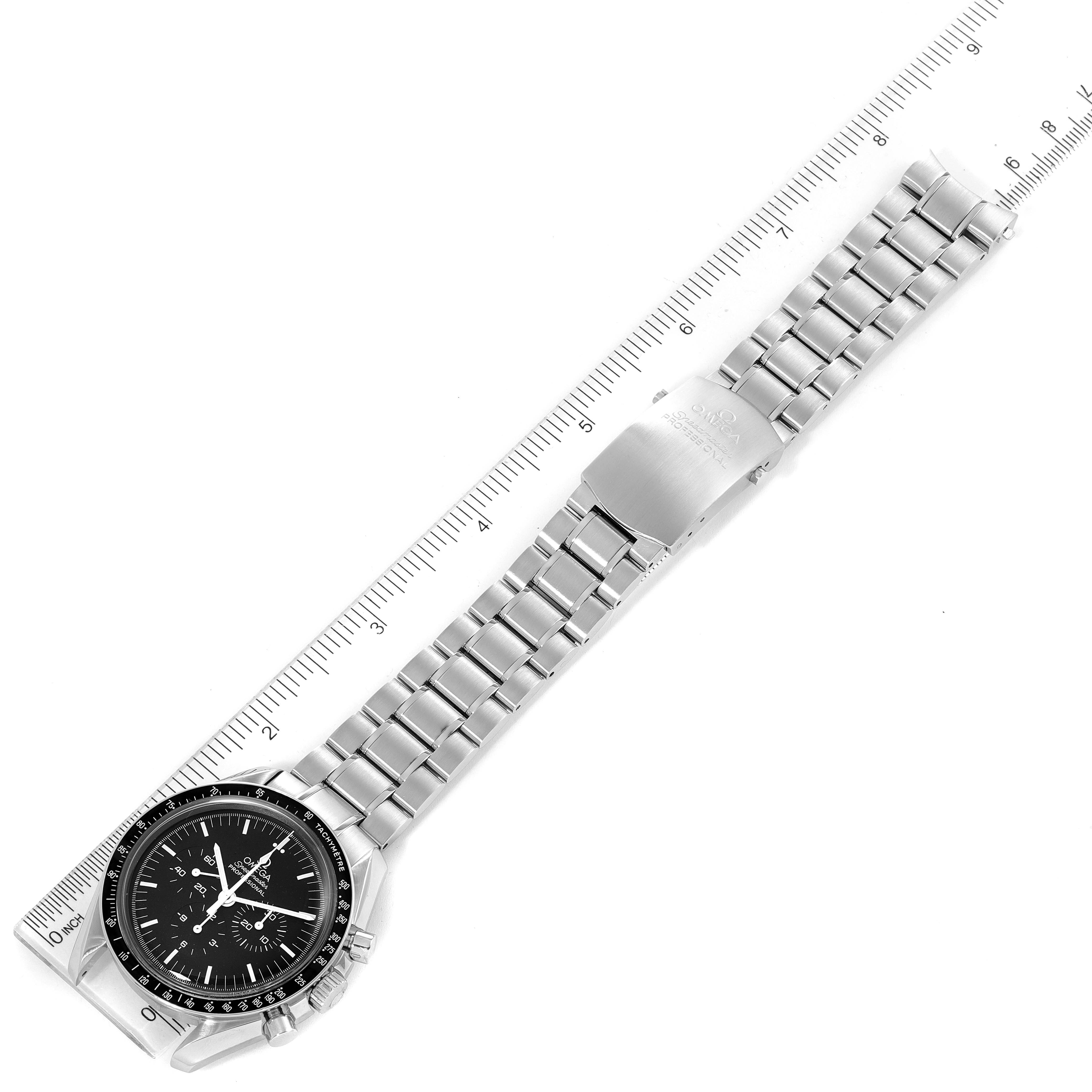 The image shows an Omega Speedmaster 3570.50.00 Men's Stainless Steel Black Dial 3570.50.00 Men's Stainless Steel Black Dial watch laid flat, alongside a ruler with its face, bracelet, and clasp visible.
