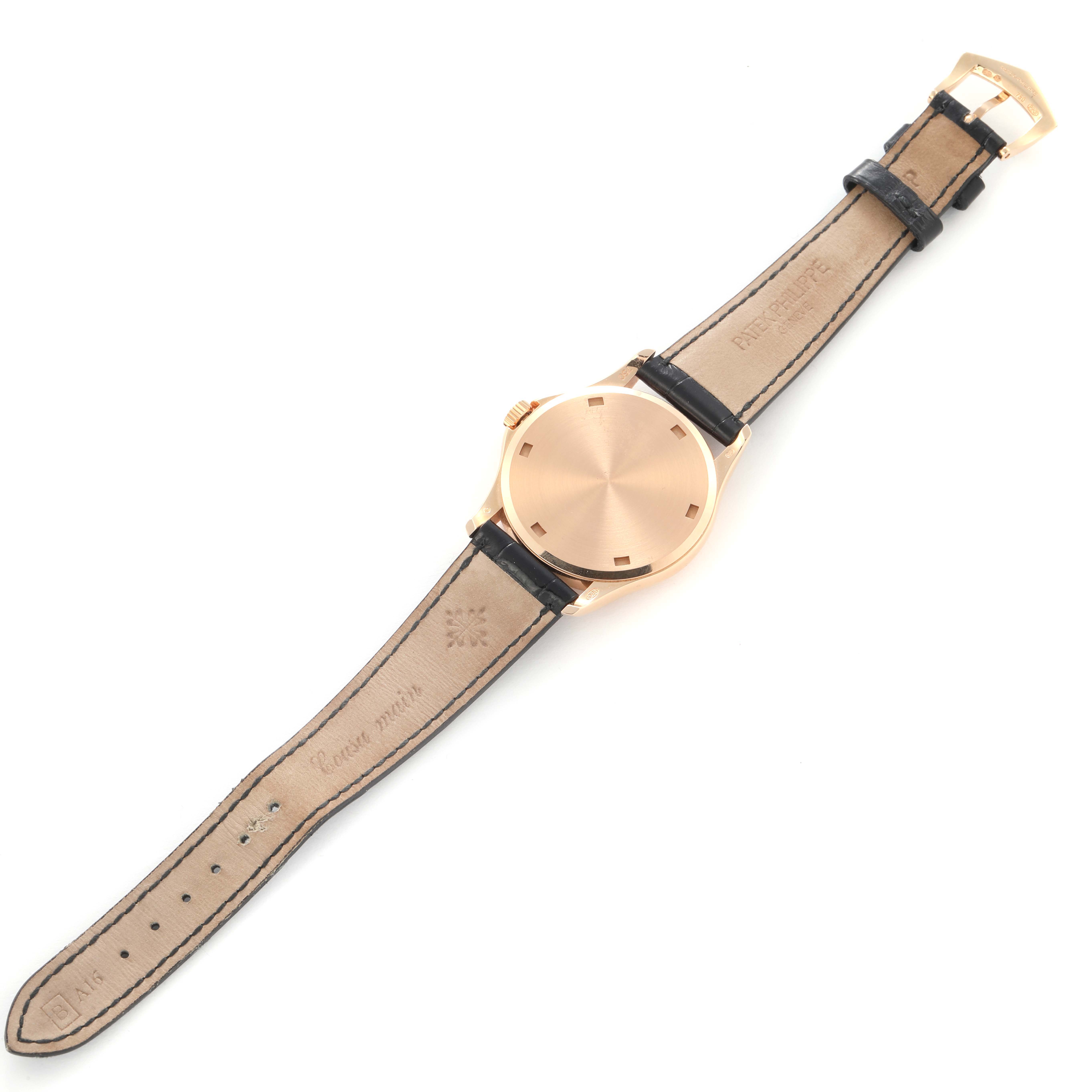 The Patek Philippe Calatrava 5115R-001 Men's Rose Gold White Dial 5115R-001 Men's Rose Gold White Dial watch is shown from an angled top view, displaying the face, leather strap, and gold buckle.