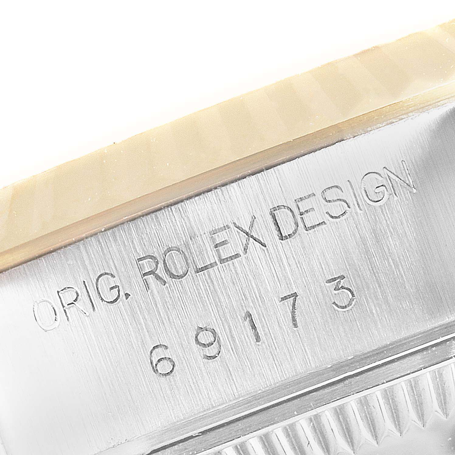 The image shows a close-up angle of the side engraving on a Rolex Datejust 69173 Women
s Steel and Gold (two tone) Champagne Dial 69173 Women
s Steel and Gold (two tone) Champagne Dial watch, displaying the text "ORIG. ROLEX DESIGN" and the model number "69173."