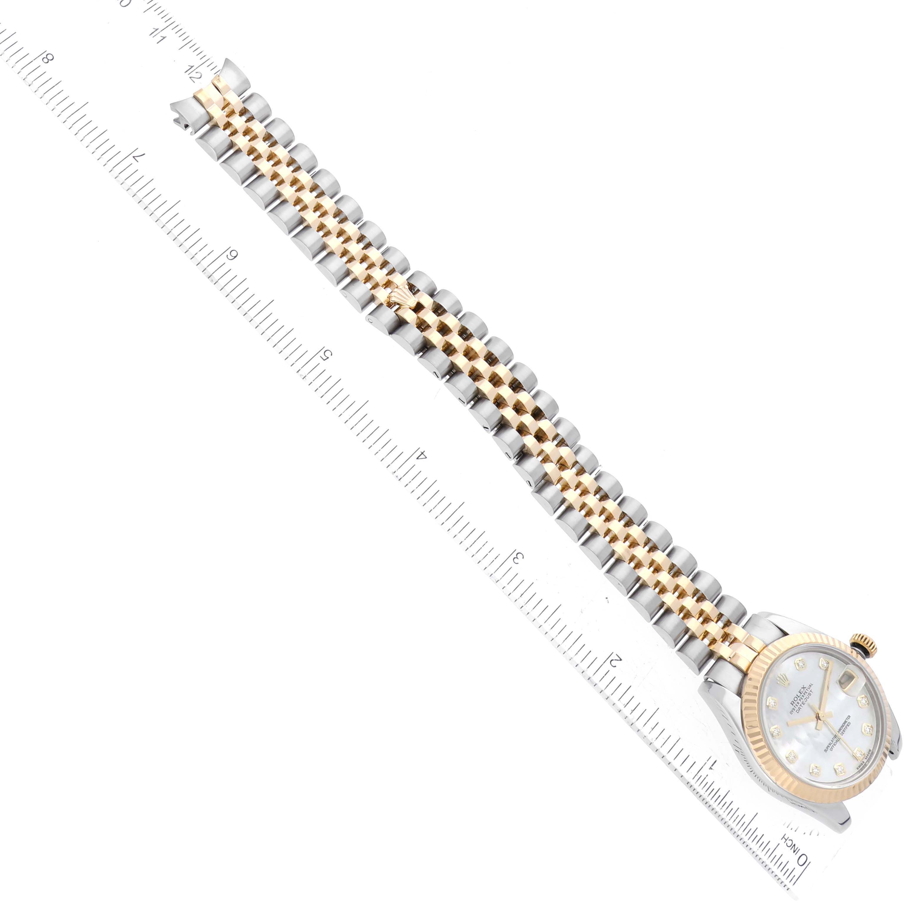 The Rolex Mid-Size 178273 Women's Steel and Gold (two tone) Mother of Pearl Dial 178273 Women's Steel and Gold (two tone) Mother of Pearl Dial watch is shown from a top view, highlighting the face and metal bracelet alongside a ruler.