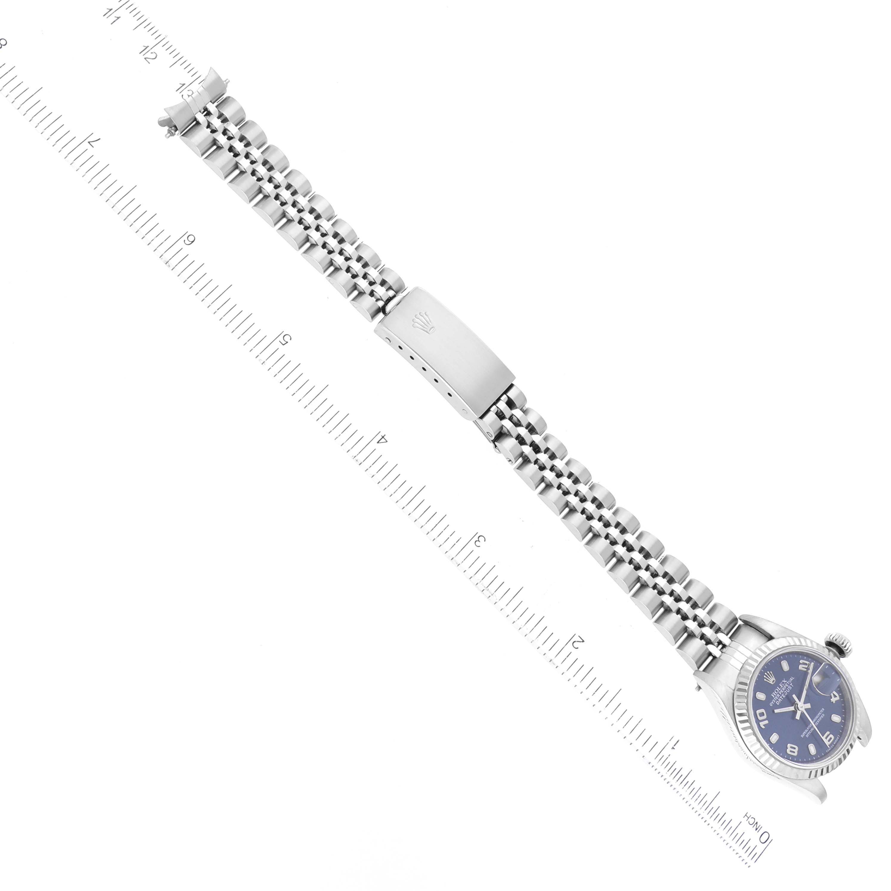 The image shows a Rolex Datejust 79174 Women's Stainless Steel Blue Dial 79174 Women's Stainless Steel Blue Dial watch from a top-down angle, highlighting its face and bracelet alongside a ruler for scale.