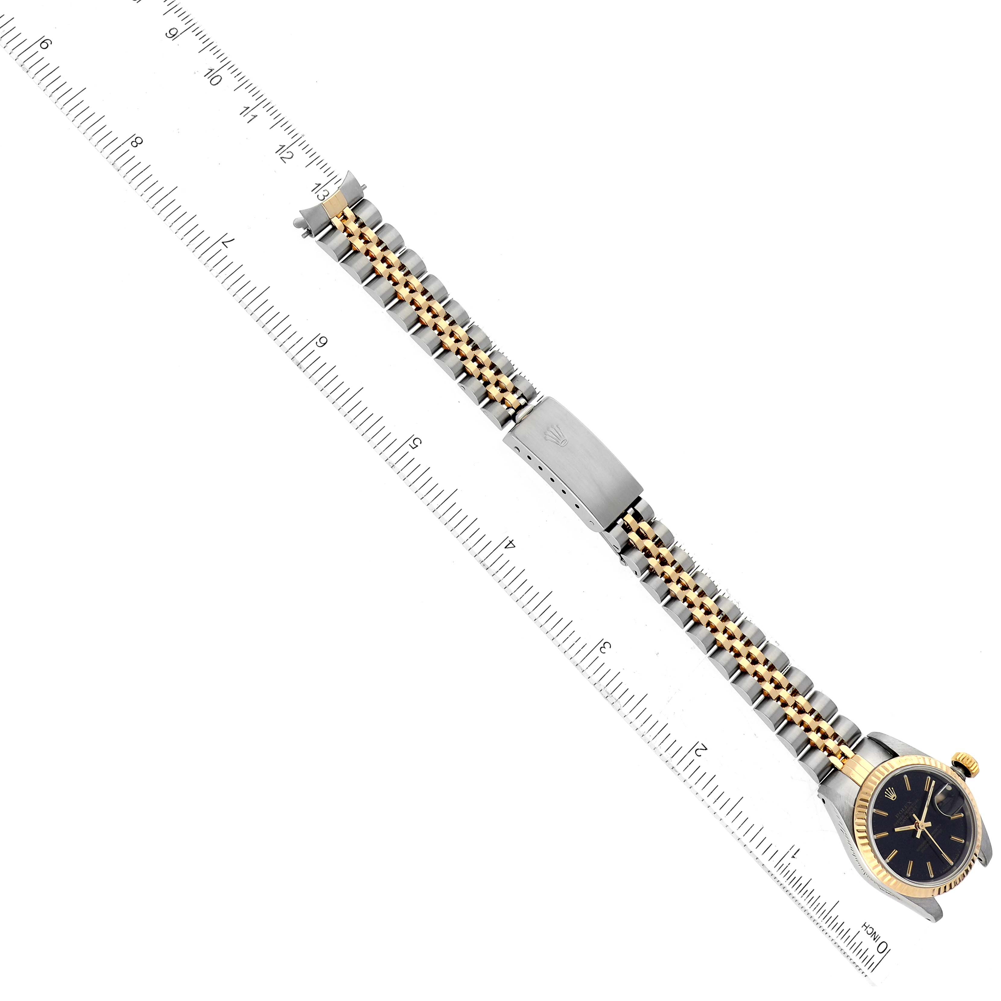 The Rolex Datejust 69173 Women's Steel and Gold (two tone) Black Dial 69173 Women's Steel and Gold (two tone) Black Dial watch is shown from a top-down angle, displaying its face, bracelet, and clasp alongside a ruler for scale.