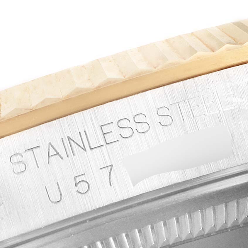 This close-up shot of the Rolex Datejust 16233 Men's Steel and Gold (two tone) Champagne Dial 16233 Men's Steel and Gold (two tone) Champagne Dial model showcases the fluted bezel and part of the engraved stainless steel case.