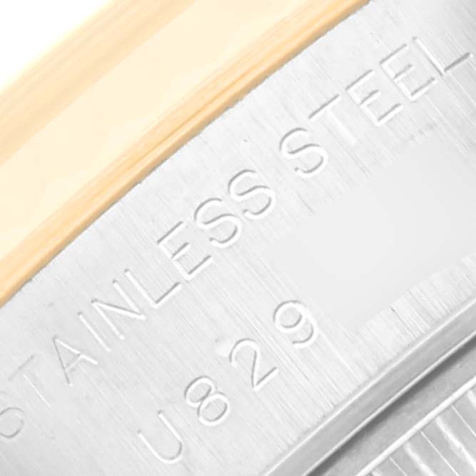 Close-up of the edge of a Rolex Datejust 69173 Women's Steel and Gold (two tone) Mother of Pearl Dial 69173 Women's Steel and Gold (two tone) Mother of Pearl Dial watch, showing the stainless steel part with embossed text and a partial view of the bezel.