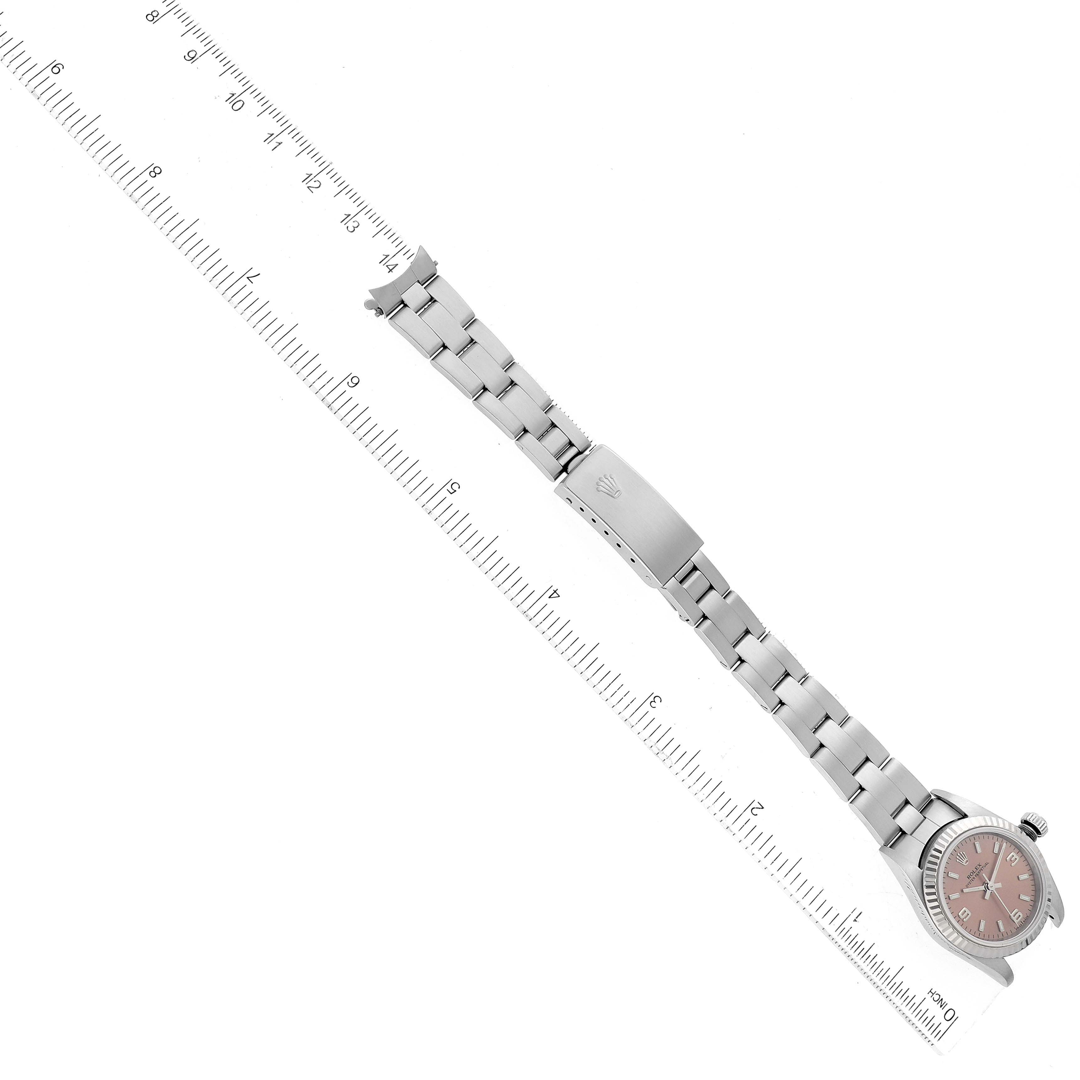 A Rolex Oyster Perpetual 76094 Women's Stainless Steel Pink Dial 76094 Women's Stainless Steel Pink Dial watch is shown flat with its bracelet extended, aligned along a ruler for measurement.