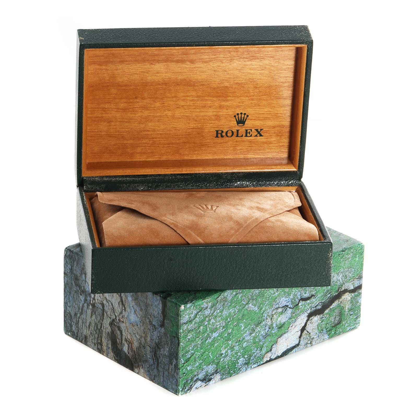 The image shows a green and wooden Rolex box for the Oysterquartz model, containing a suede pouch, viewed from the front.