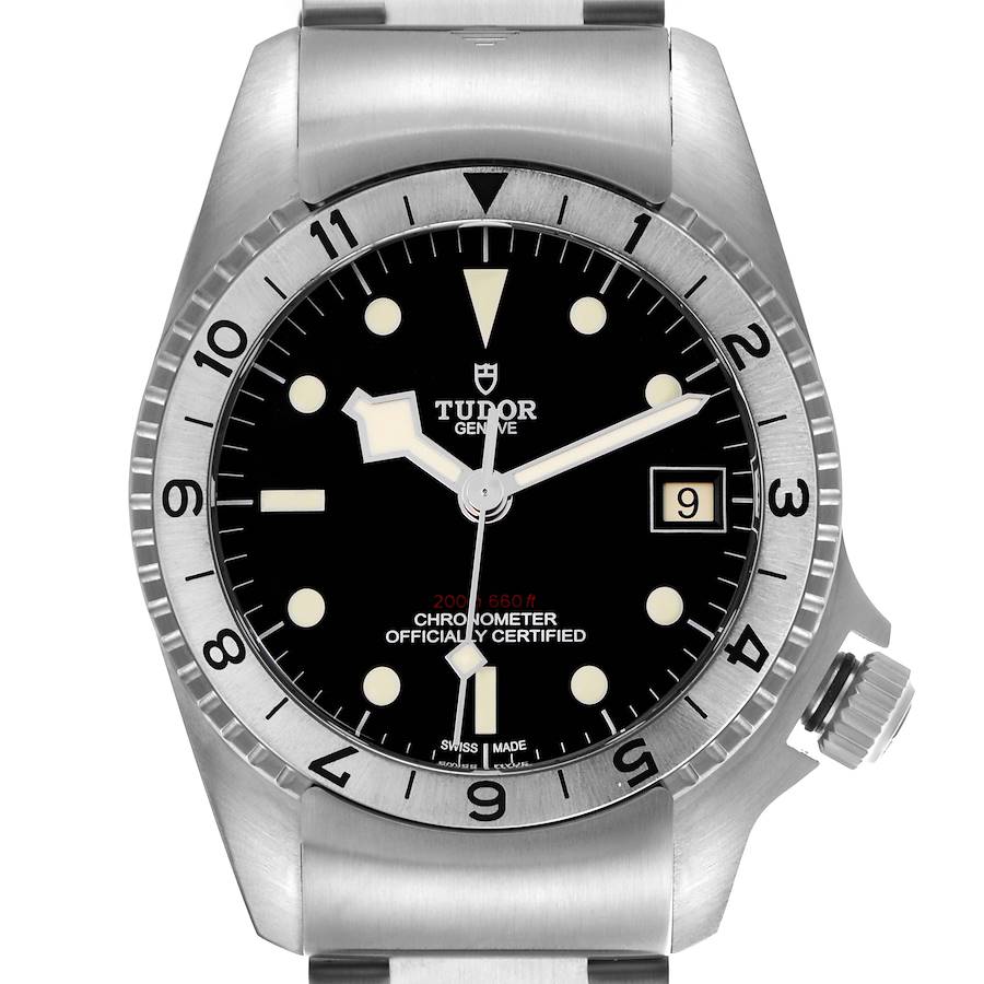 The Tudor Heritage Black Bay watch is shown from a front angle, displaying the dial, bezel, crown, and part of the bracelet.