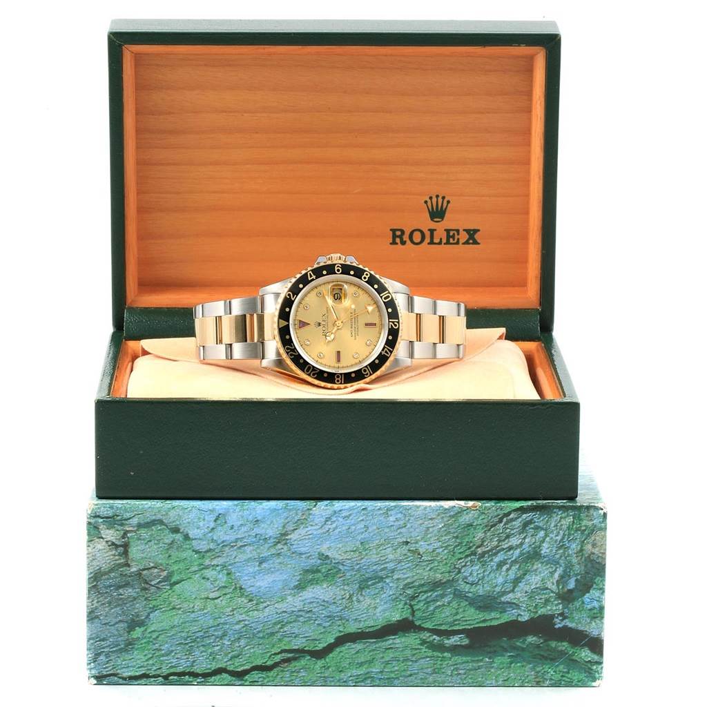 The Rolex 16713 Men
s Stainless Steel Champagne Dial 16713 Men
s Stainless Steel Champagne Dial GMT-Master II Yellow Gold Steel Diamond Ruby Serti Dial Watch 16713 is displayed frontally, inside an open Rolex 16713 Men
s Stainless Steel Champagne Dial 16713 Men
s Stainless Steel Champagne Dial box.