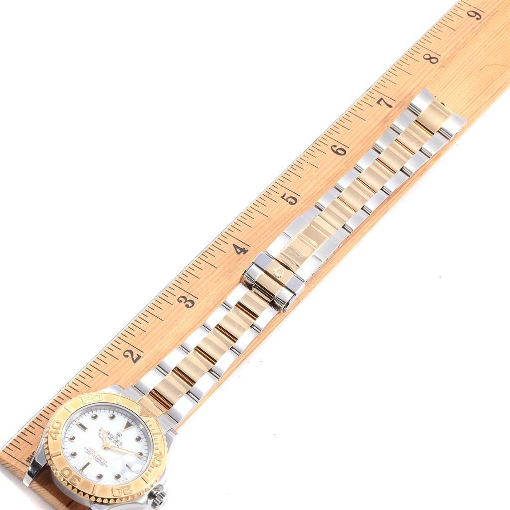 The Rolex 168623 Steel and Gold (two tone) White Dial 168623 Steel and Gold (two tone) White Dial Yachtmaster 35 Midsize Steel Yellow Gold Watch 168623 is shown from an overhead angle with its full band extended along a ruler.
