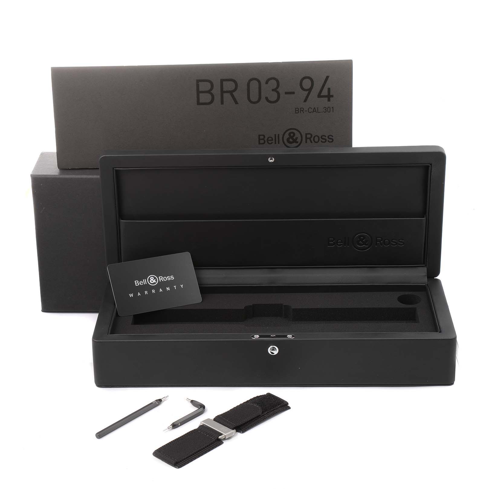The image shows the packaging, warranty card, tools, and strap for the Bell & Ross BR 03-94 Chronograph model.