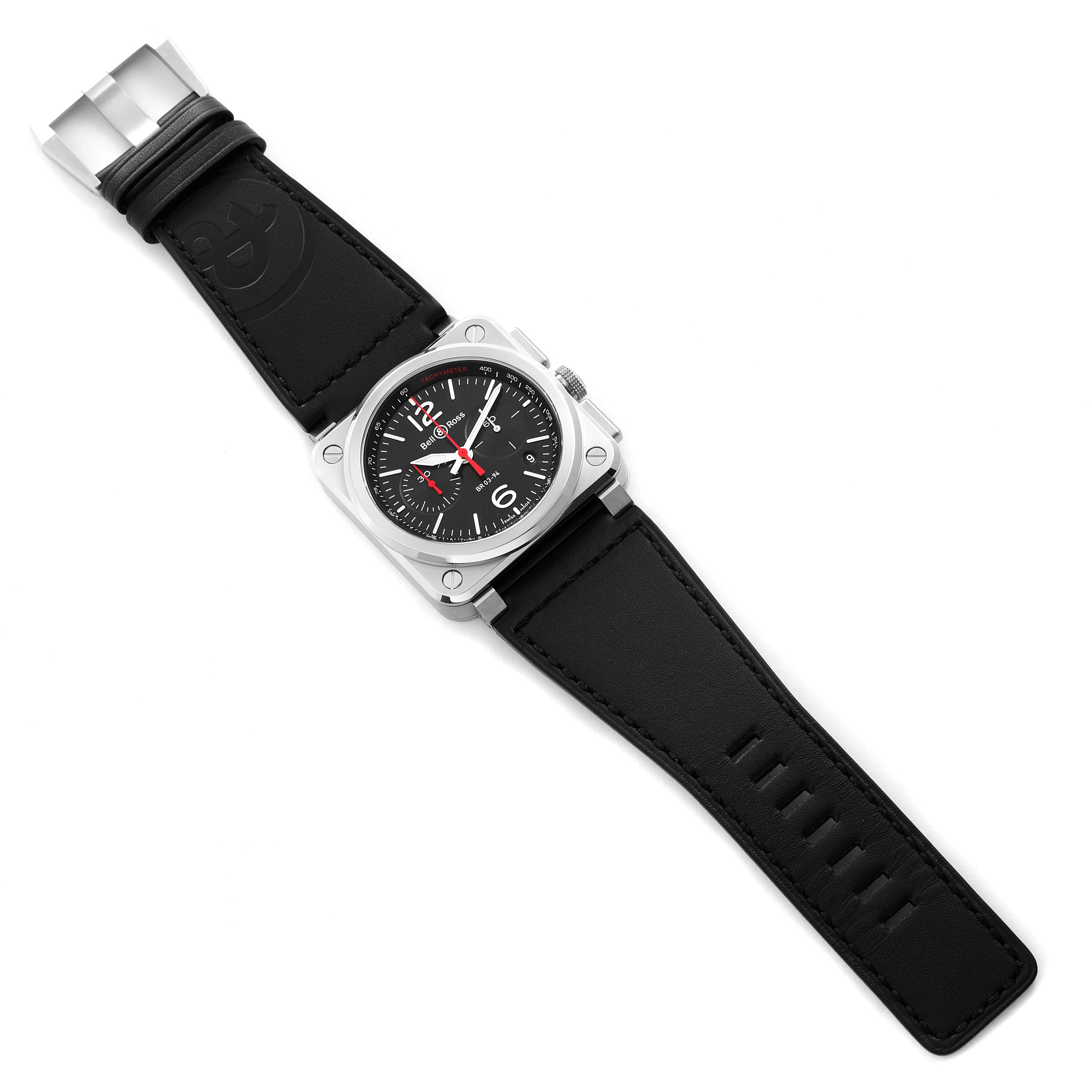 The image shows a top-down view of the Bell & Ross Chronograph watch, including its black strap, square case, and dial with red accents.