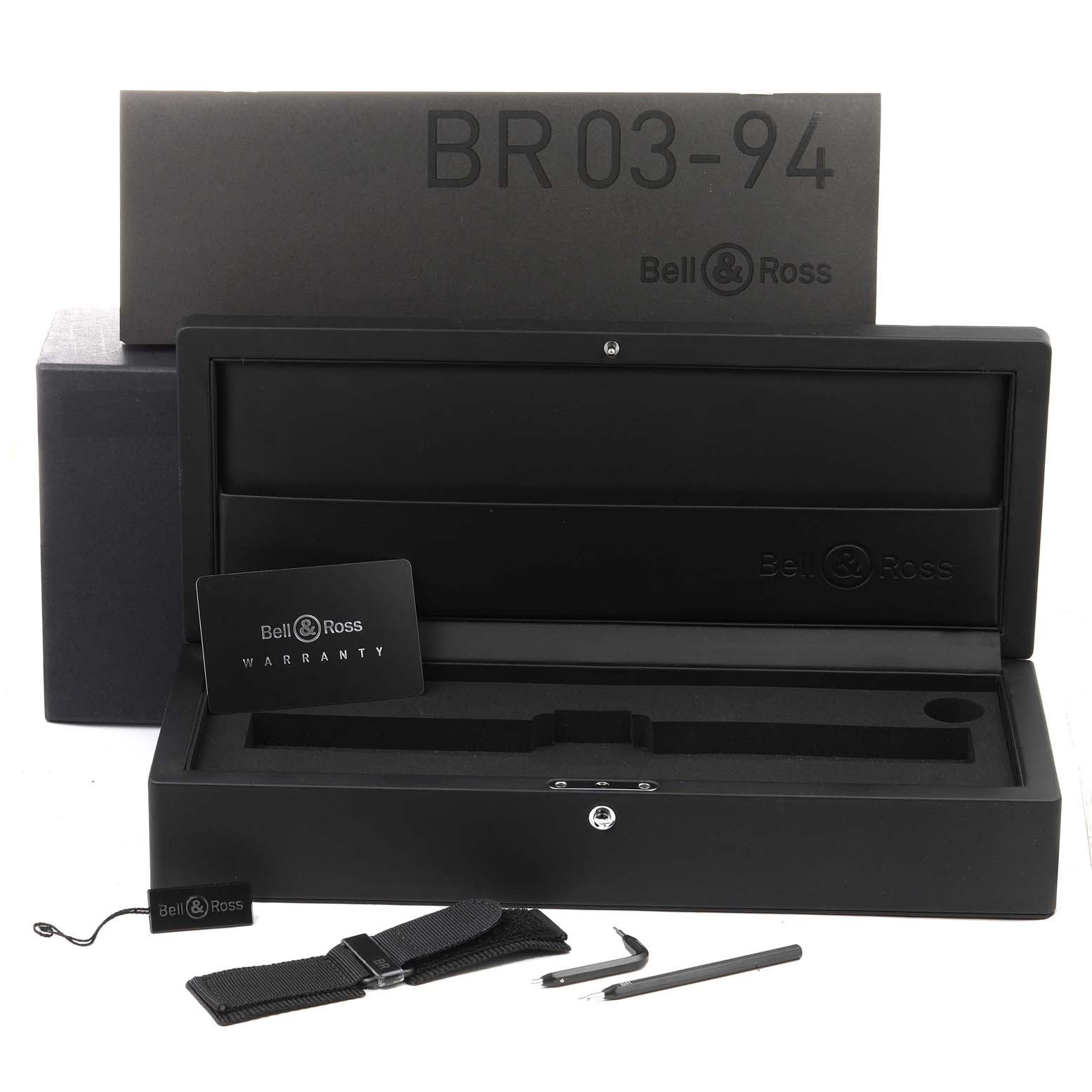 The image shows the packaging, warranty card, extra band, and tools for the Bell & Ross BR 03-94 Chronograph watch.