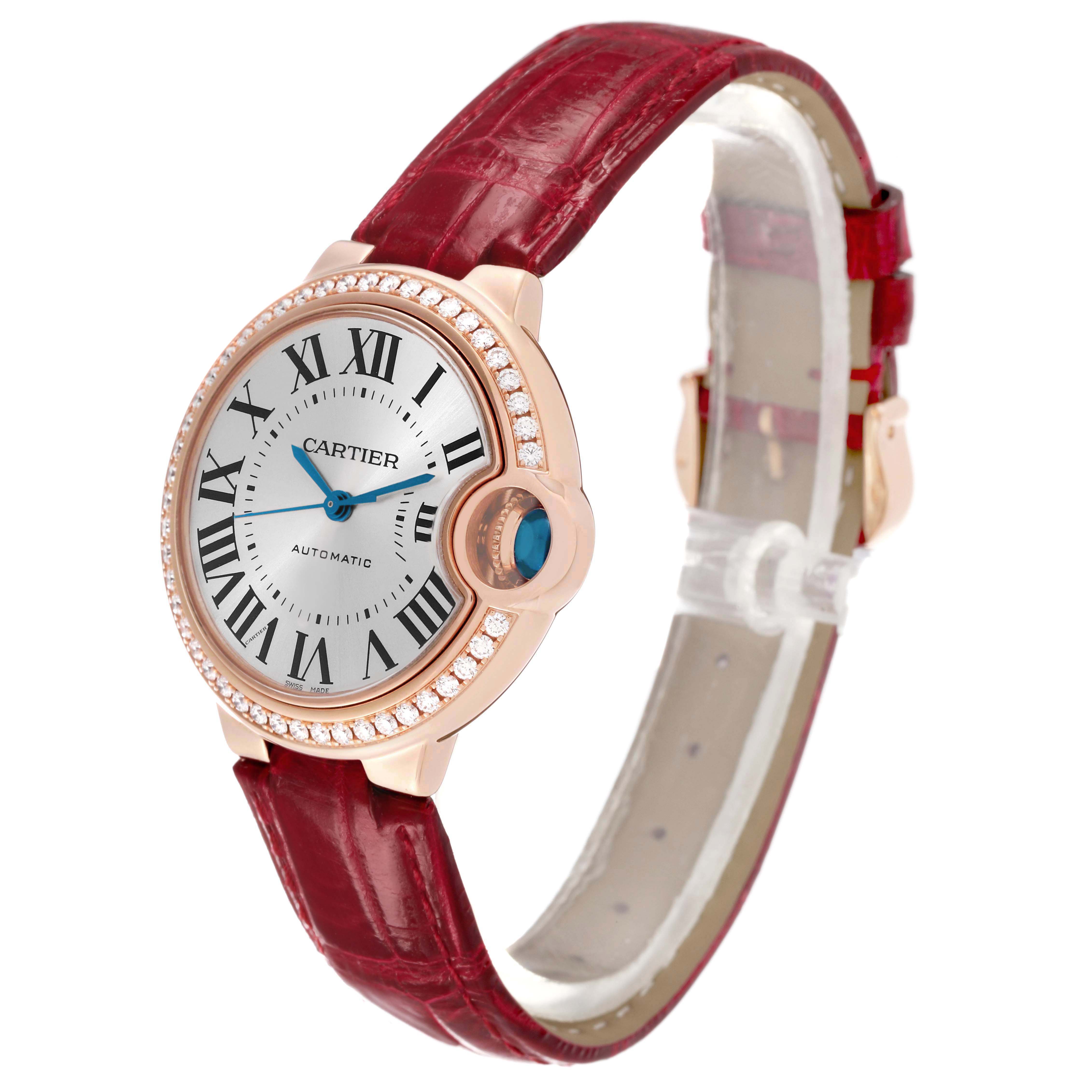 The Cartier Ballon Bleu WJBB0033 Women's Rose Gold Silver Dial watch is shown at a three-quarter angle, displaying its face, red leather strap, and diamond-encrusted bezel.