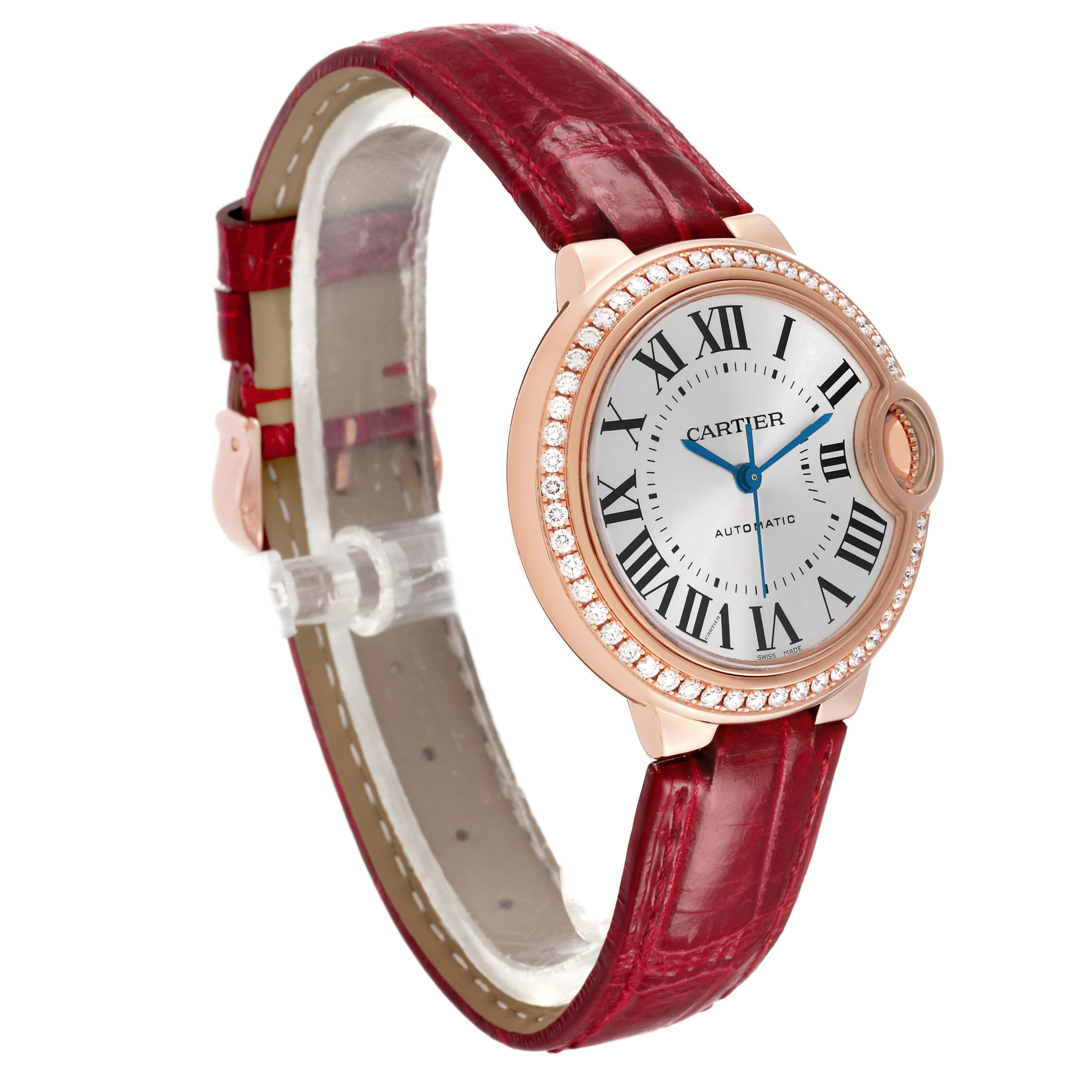 The Cartier Ballon Bleu WJBB0033 Women's Rose Gold Silver Dial watch is shown at a three-quarter angle, highlighting its red strap and diamond bezel.