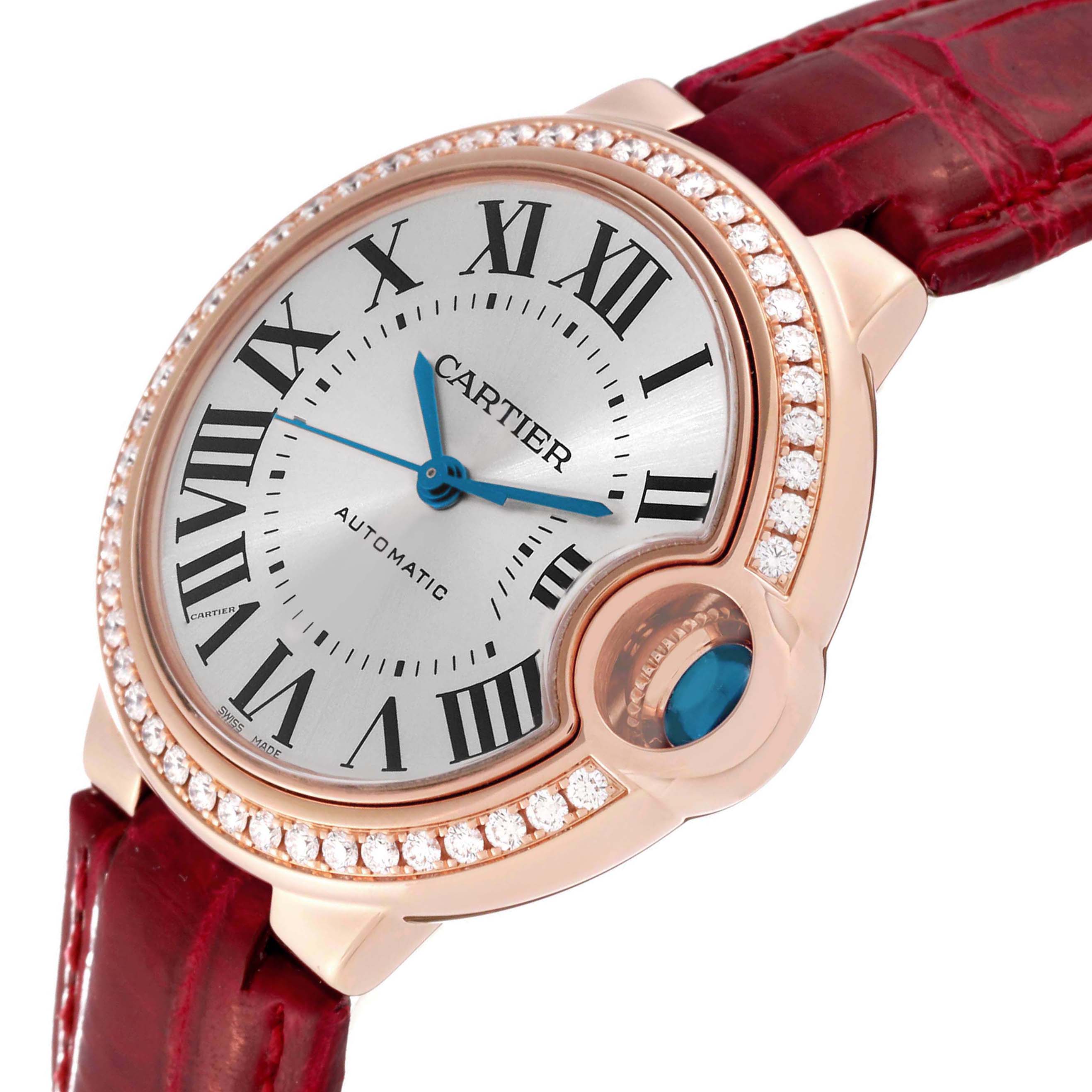The Ballon Bleu by Cartier is shown at an angled close-up, highlighting the face, diamond bezel, and red leather strap.