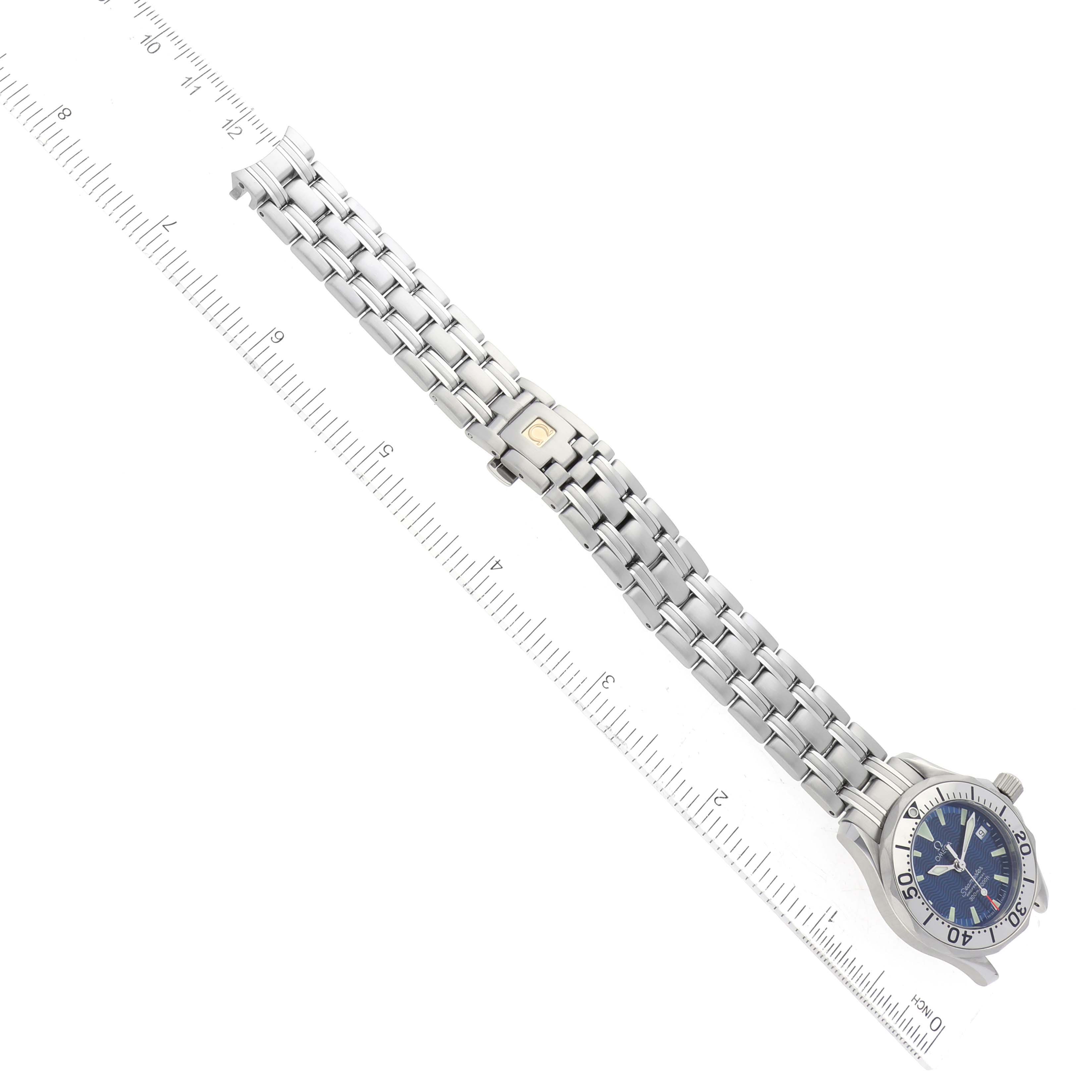 The image shows an Omega 2283.80.00 Women's Stainless Steel Blue Dial 2283.80.00 Women's Stainless Steel Blue Dial Seamaster Diver Quartz 28mm Steel Ladies Watch 2283.80.00 laid flat with a ruler for scale.