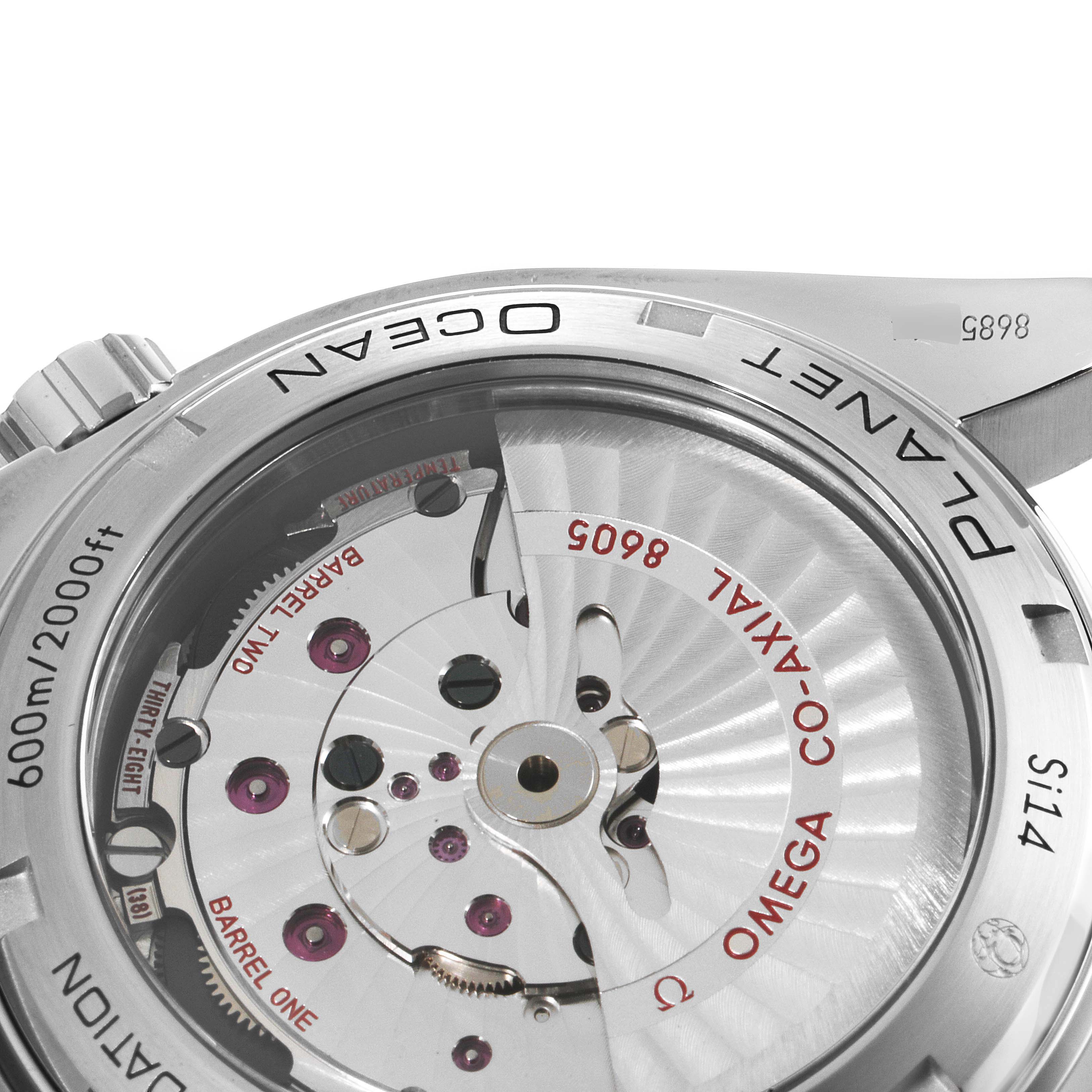 The image shows a close-up view of the back of the Omega Planet Ocean 232.30.44.22.03.001 Men's Stainless Steel Blue Dial 232.30.44.22.03.001 Men's Stainless Steel Blue Dial watch, highlighting its movement mechanism and inscriptions.