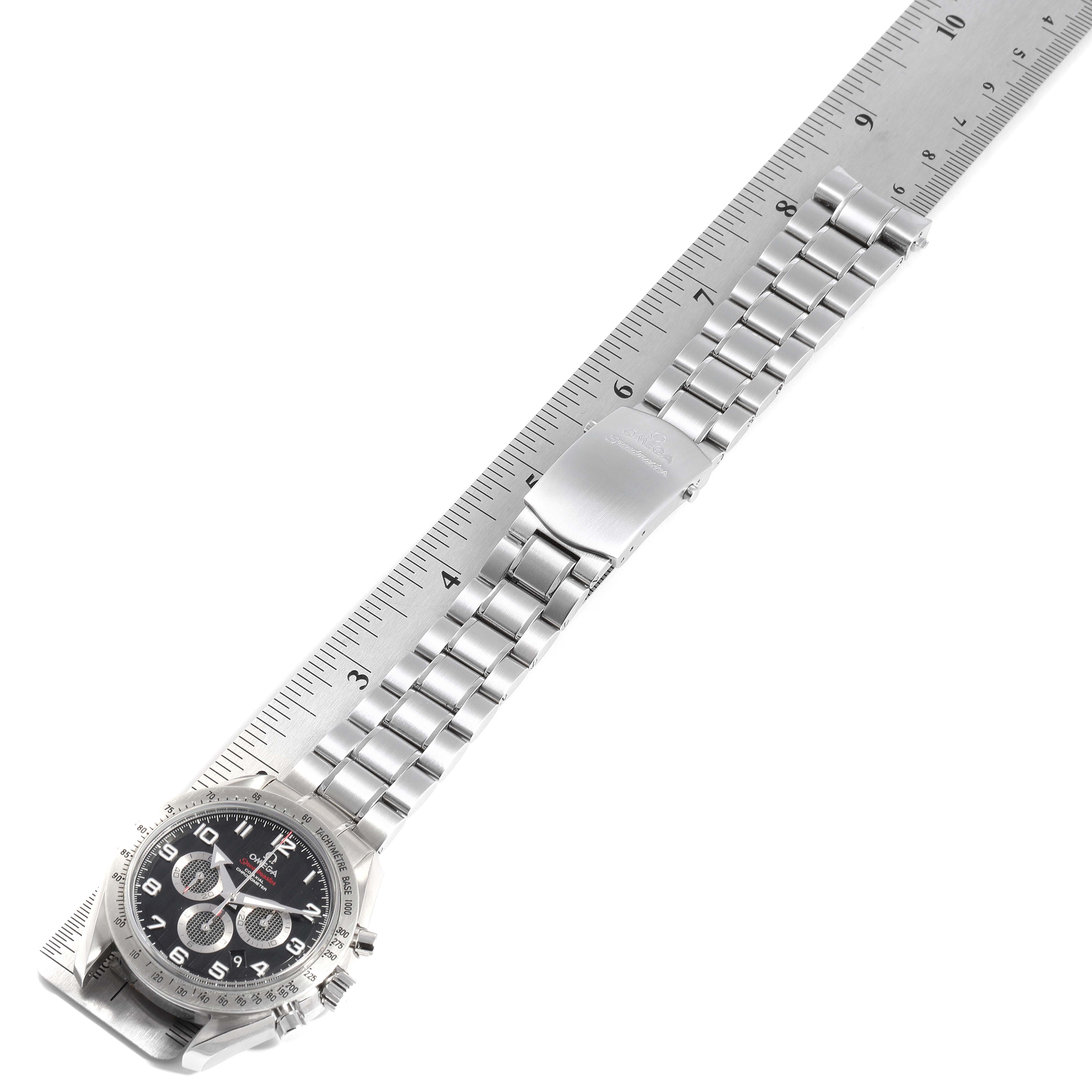 The Omega Speedmaster 321.10.44.50.01.001 Men's Stainless Steel Black Dial 321.10.44.50.01.001 Men's Stainless Steel Black Dial watch is shown flat with the bracelet extended alongside a ruler, displaying its face and clasp.