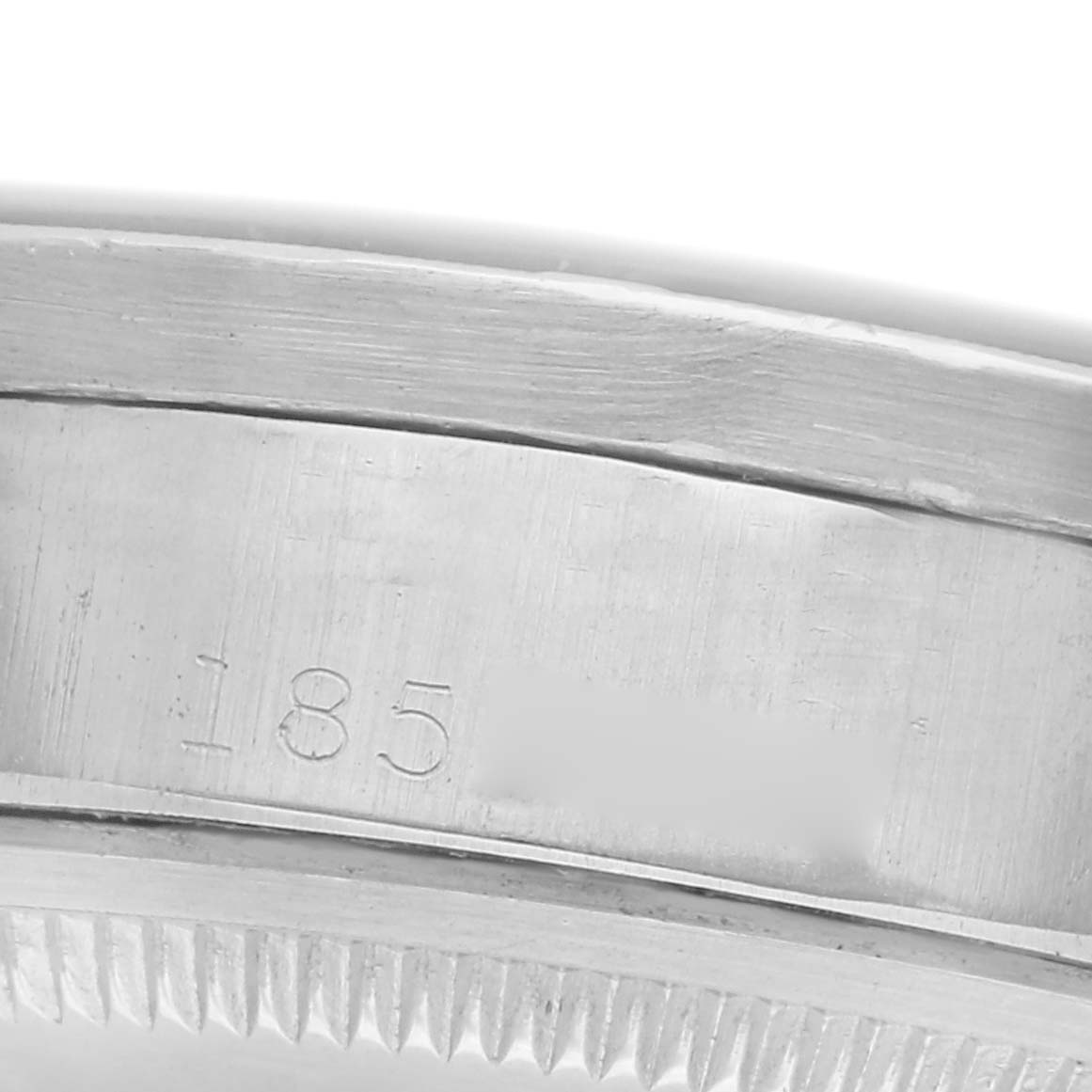 The image shows a close-up of the side engraving and fluted bezel edge of a Rolex Date model watch.