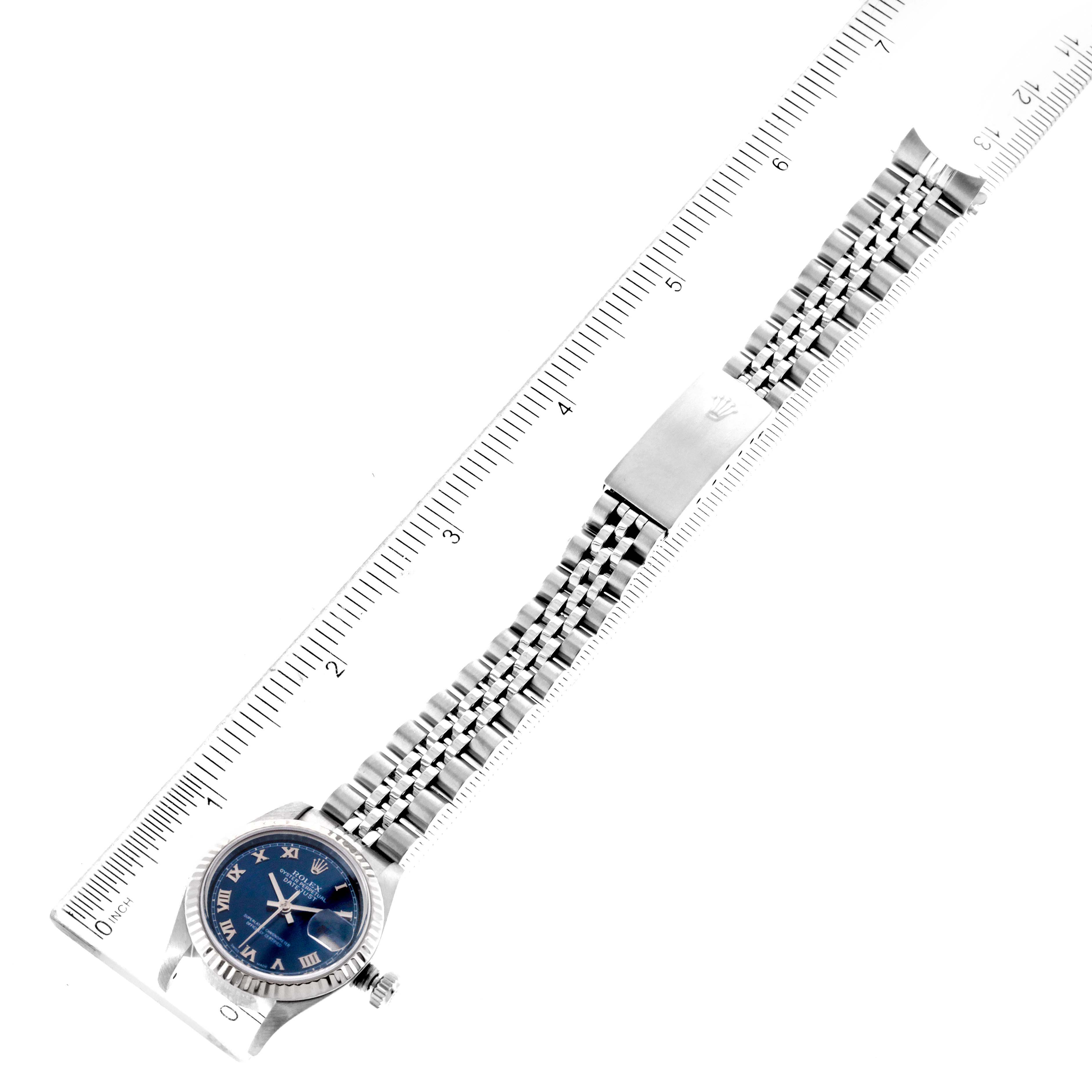 The image shows a Rolex Datejust 79174 Women
s Stainless Steel Blue Dial 79174 Women
s Stainless Steel Blue Dial watch laid flat with its face and bracelet visible, aligned next to a ruler.