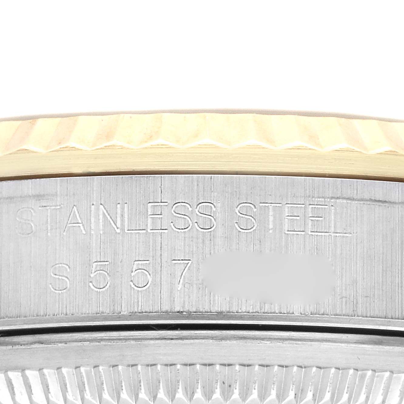 This close-up image of a Rolex Datejust 16233 Men's Steel and Gold (two tone) Champagne Dial 16233 Men's Steel and Gold (two tone) Champagne Dial watch shows the stainless steel case engraved with text and a portion of the fluted bezel.