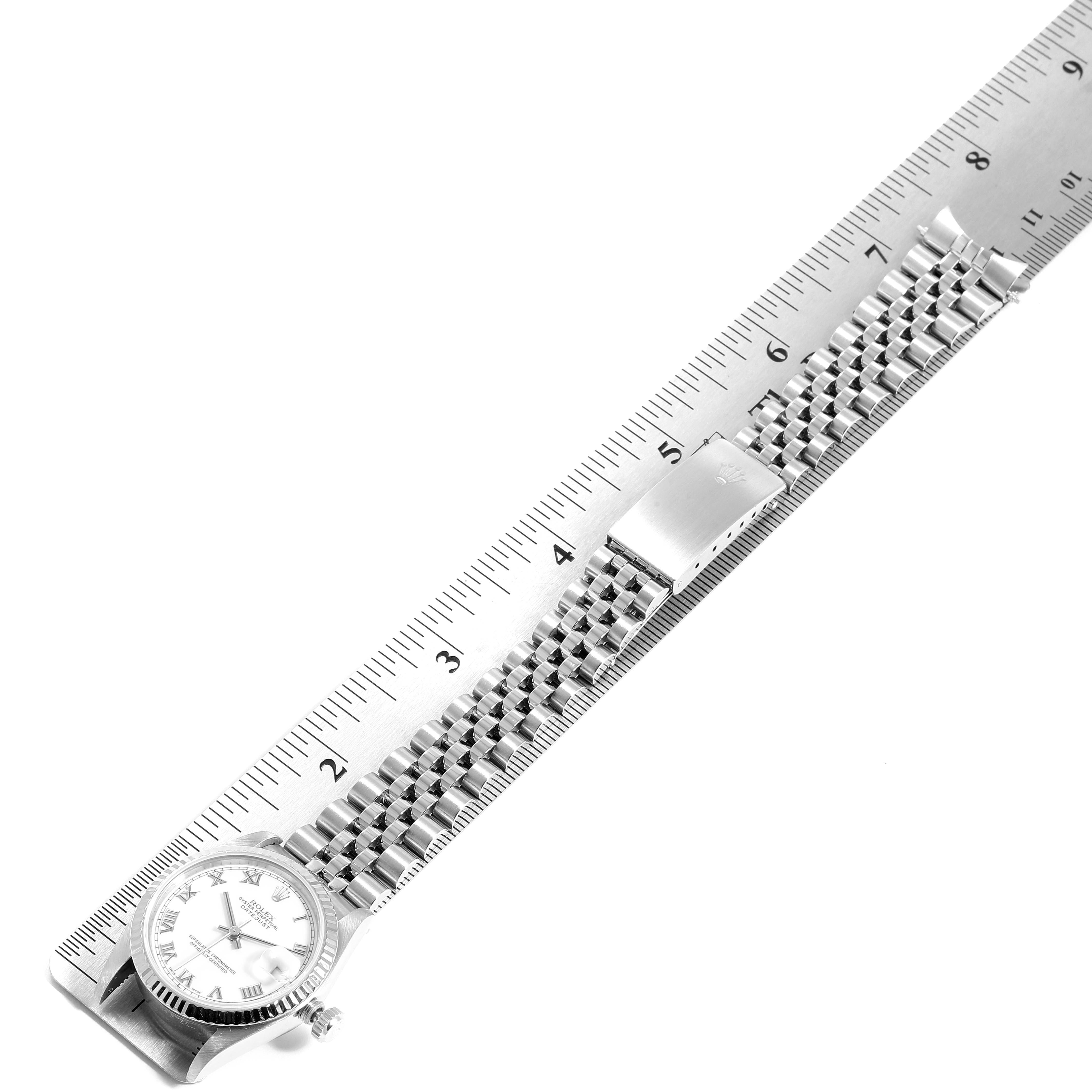 The image shows a Mid-Size Rolex watch laid flat alongside a ruler, displaying the entire watch with its face and bracelet.