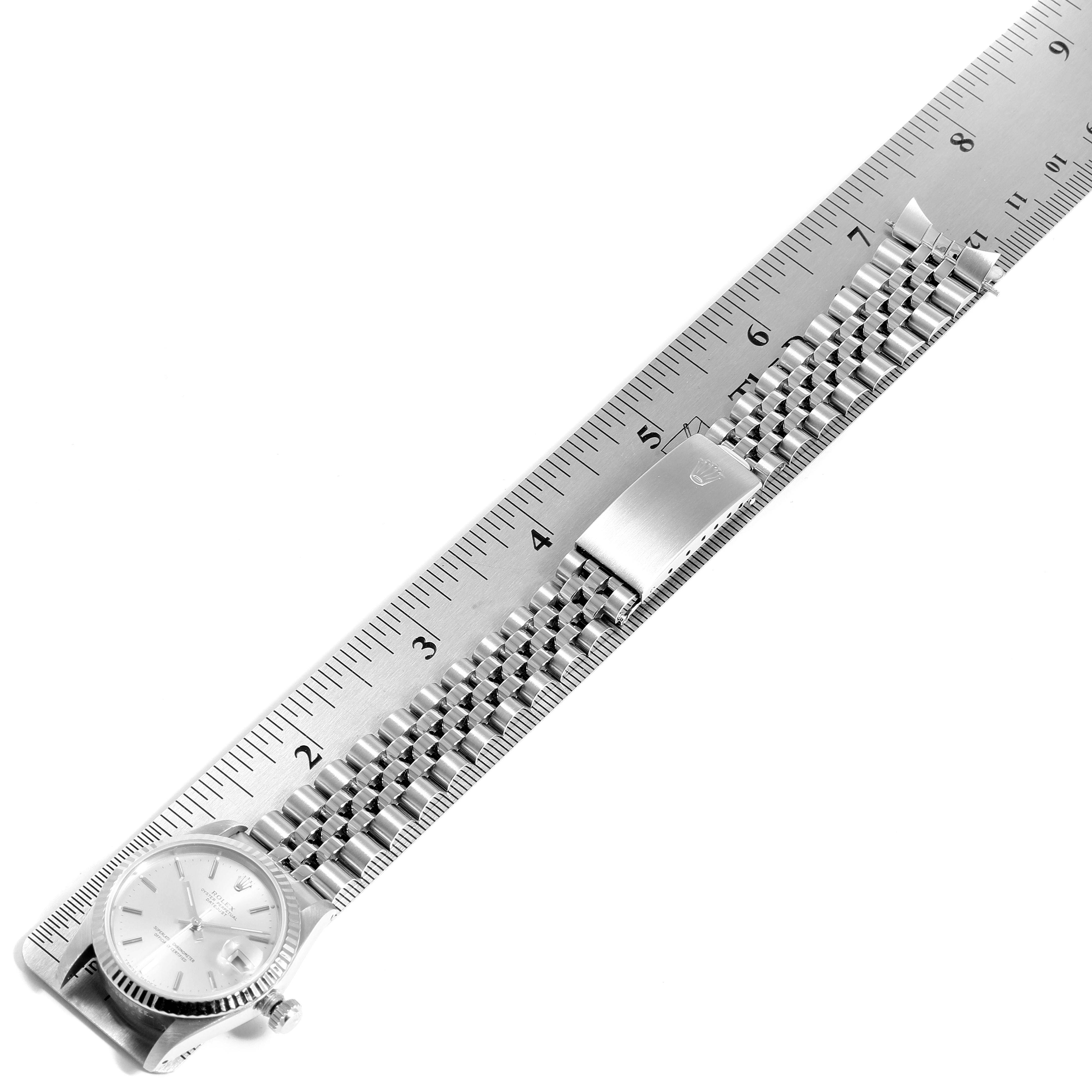 The image shows a top view of a Mid-Size Rolex watch alongside a ruler, highlighting its face, bezel, and metal bracelet.