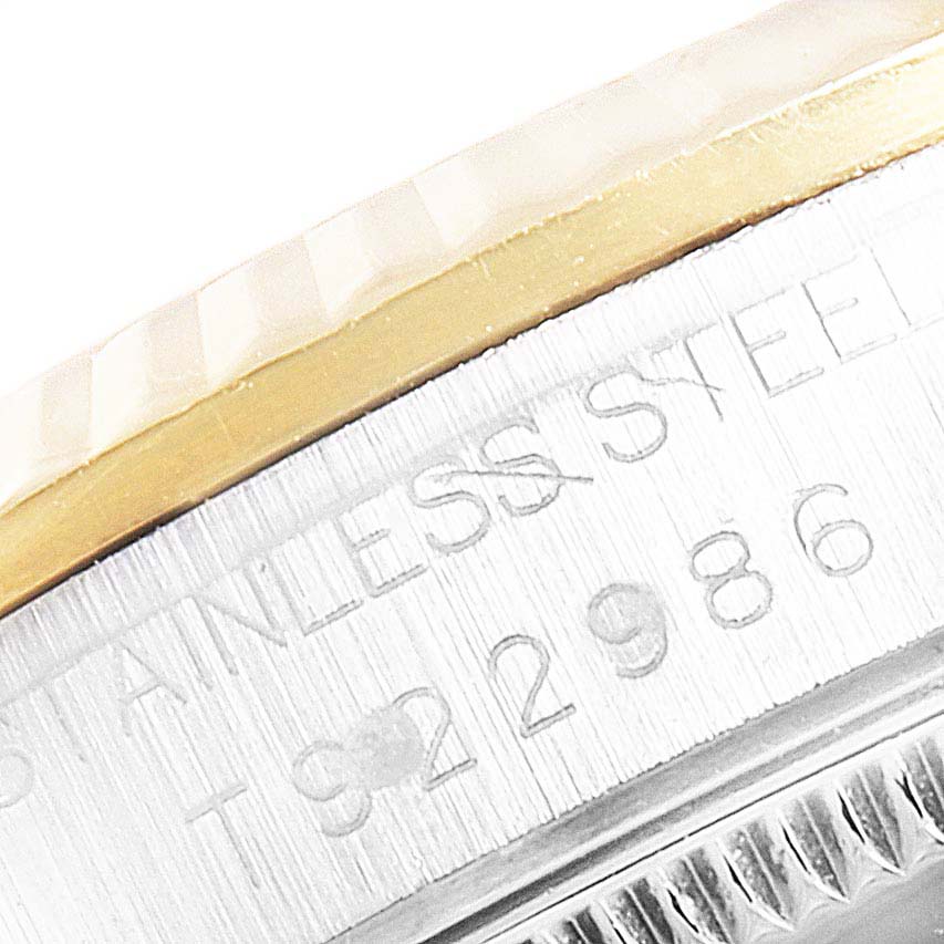 The image shows a close-up angle of the side of a Rolex Mid-Size 68273 Women
s Steel and Gold (two tone) Silver Dial 68273 Women
s Steel and Gold (two tone) Silver Dial model watch, highlighting the fluted bezel and serial number engraving on the stainless steel case.