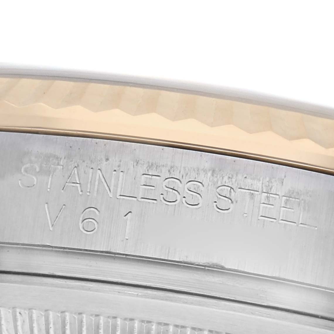 The image shows a close-up of the side of a Rolex Datejust 116233 Men's Steel and Gold (two tone) Champagne Dial 116233 Men's Steel and Gold (two tone) Champagne Dial watch, focusing on the stainless steel case edge and engraved text.