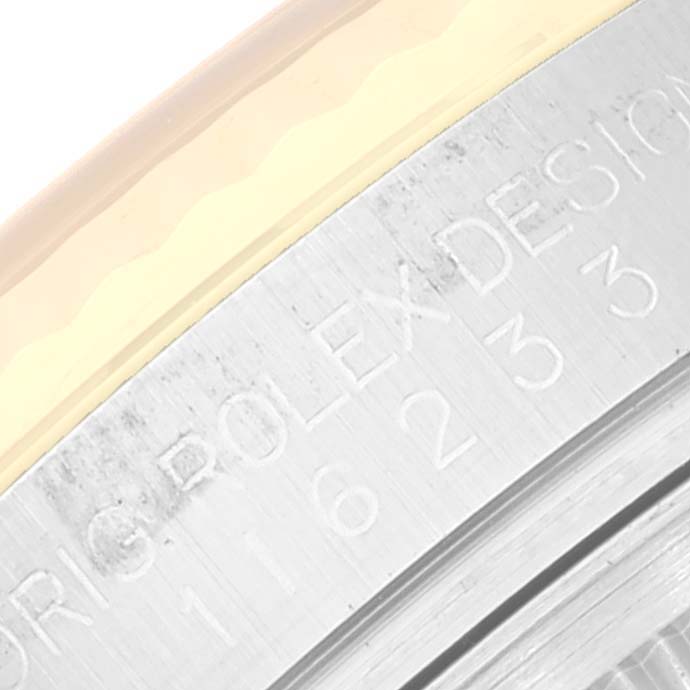 This close-up image of a Rolex Datejust 116233 Men's Steel and Gold (two tone) Black Dial 116233 Men's Steel and Gold (two tone) Black Dial watch shows an engraved part of its bezel and case.