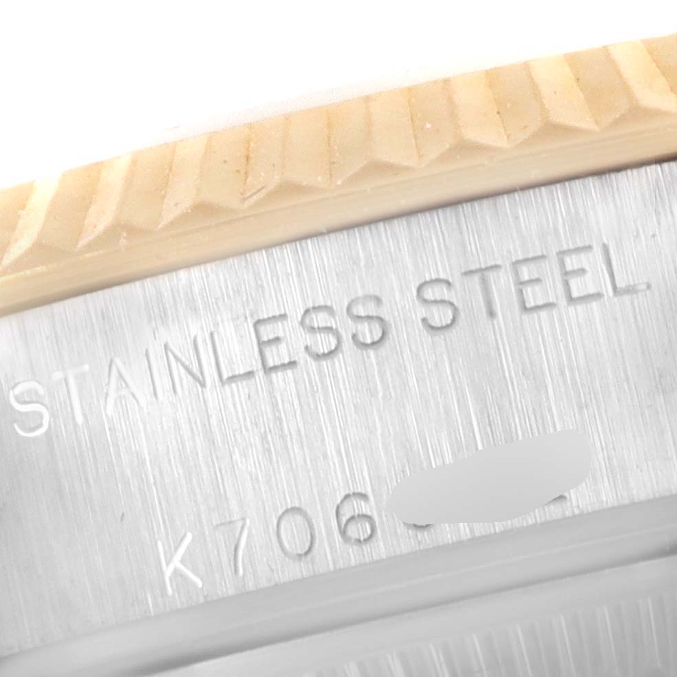 This close-up image shows the "STAINLESS STEEL" engraving and part of the fluted bezel on a Rolex Datejust 79173 Women
s Steel and Gold (two tone) Red Dial 79173 Women
s Steel and Gold (two tone) Red Dial watch.