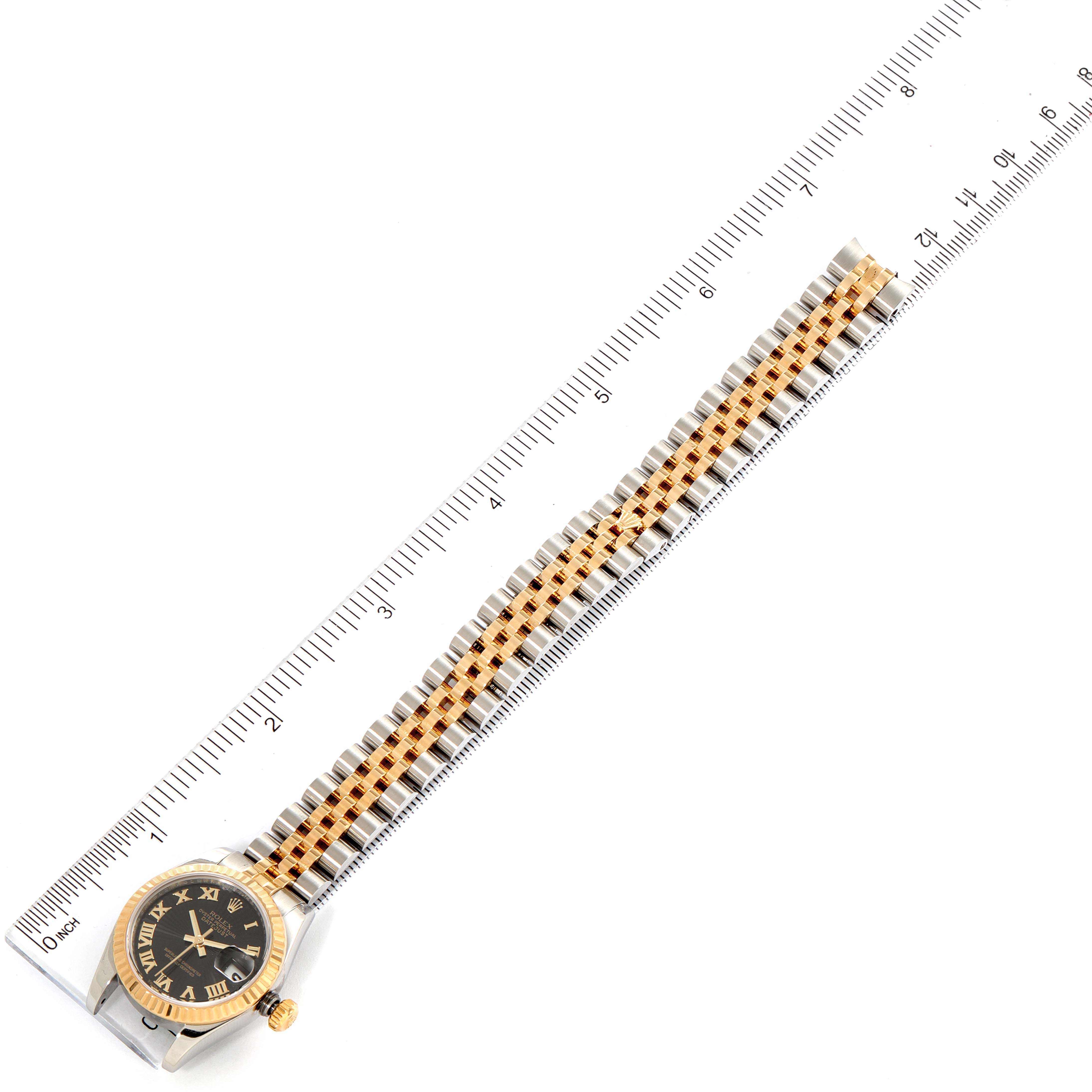 The Rolex Datejust 179173 Women
s Steel and Gold (two tone) Black Dial 179173 Women
s Steel and Gold (two tone) Black Dial watch is shown from a top-down angle, including the face, bezel, crown, and band measured against a ruler.