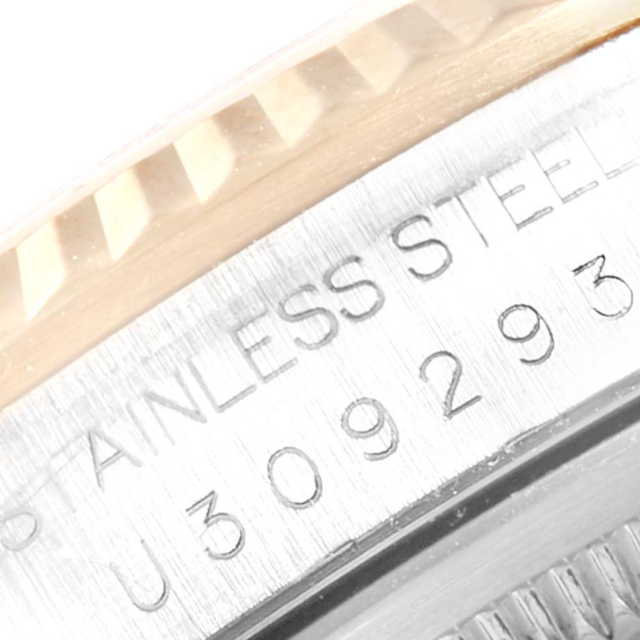 This close-up image of the Rolex Datejust 16233 Men's Steel and Gold (two tone) Champagne Dial 16233 Men's Steel and Gold (two tone) Champagne Dial watch shows part of the fluted bezel and the engraved serial number on the case.