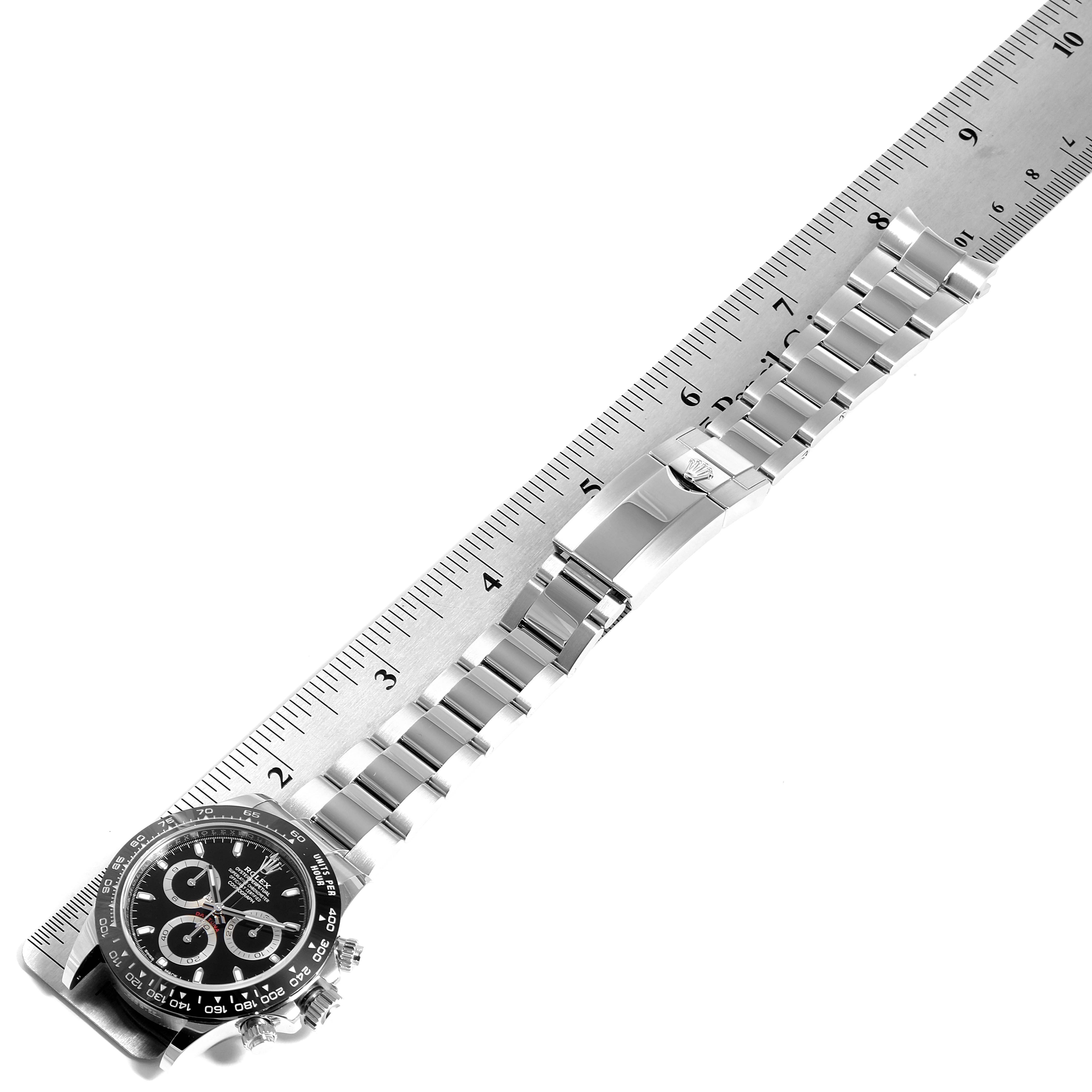The image shows a flat-lay view of a Rolex Daytona 116500 Men's Stainless Steel Black Dial 116500 Men's Stainless Steel Black Dial watch with its band aligned next to a ruler.
