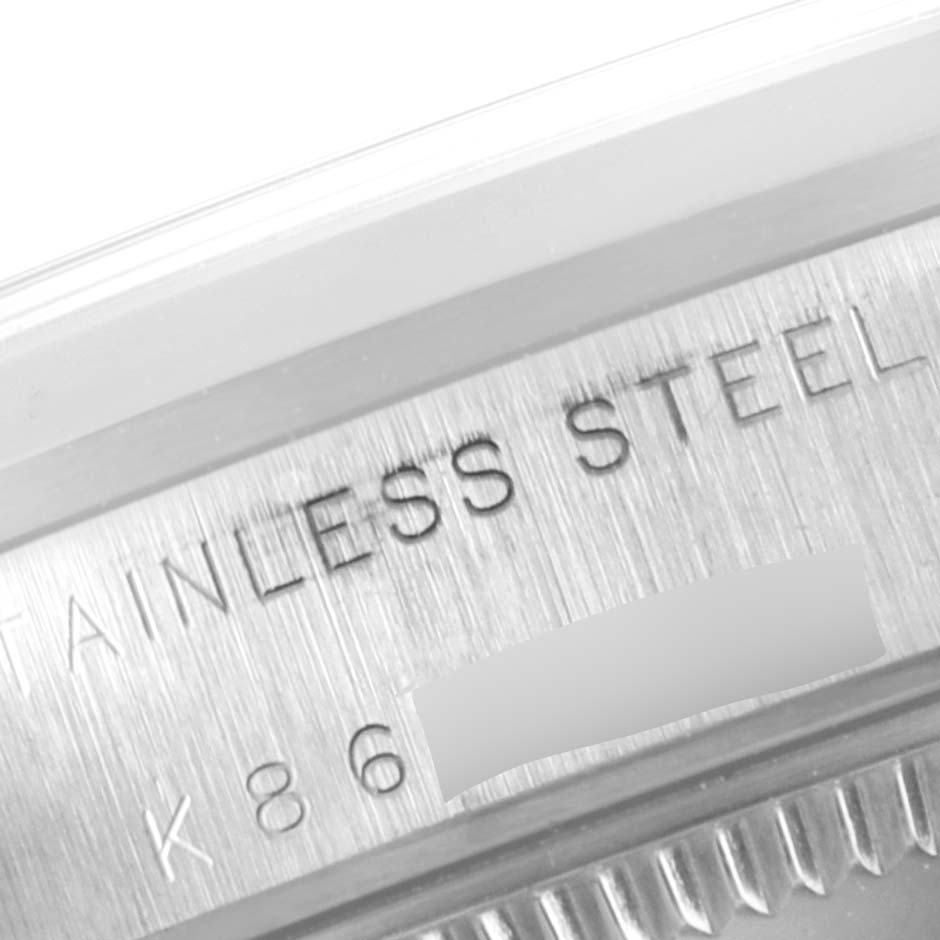 This image shows a close-up of the brushed stainless steel casing of a mid-size Rolex watch, highlighting the engraved text and part of the bezel.