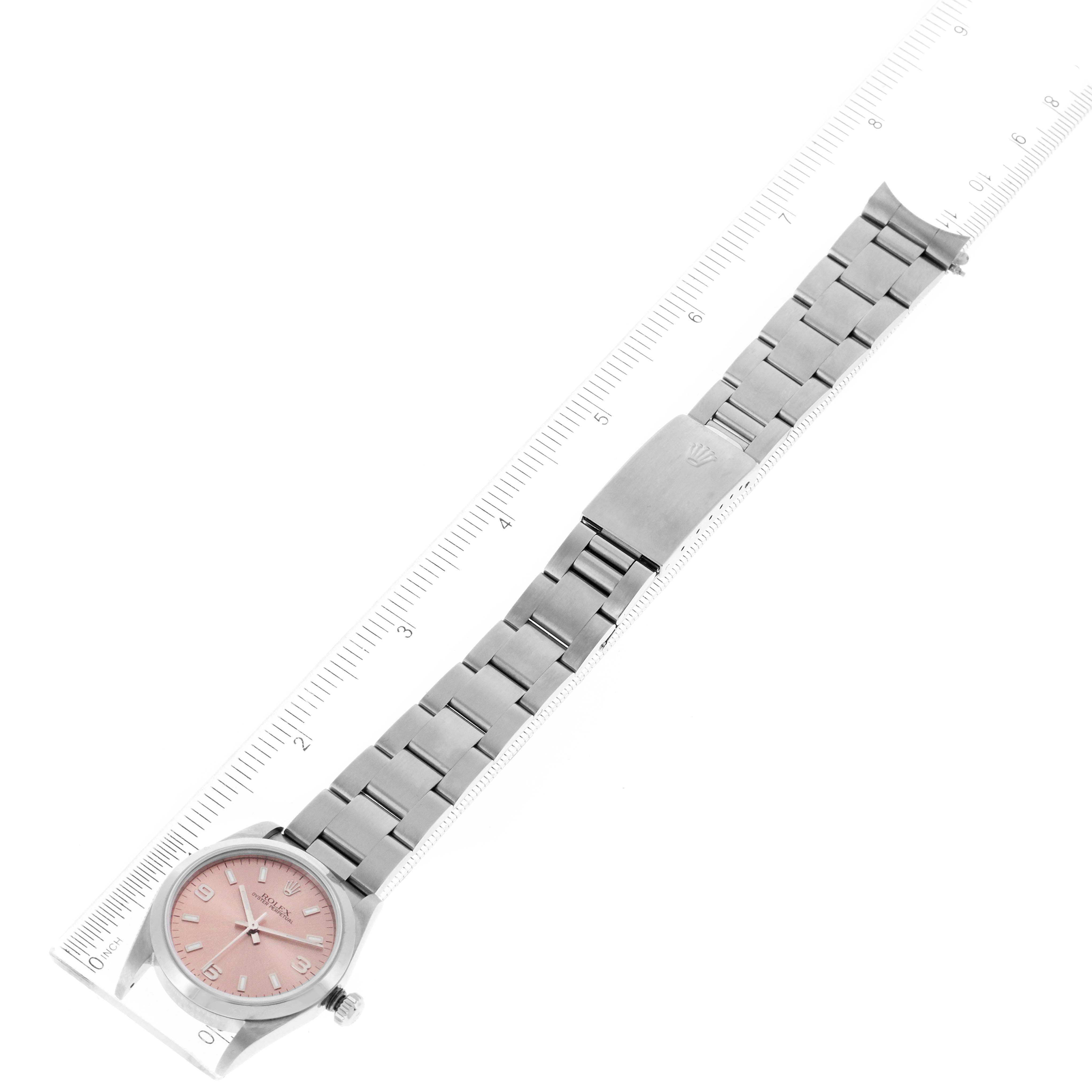 The image shows a Rolex Mid-Size 77080 Women
s Stainless Steel Pink Dial 77080 Women
s Stainless Steel Pink Dial watch laid flat, with its face, bracelet, and clasp visible next to a ruler for scale.
