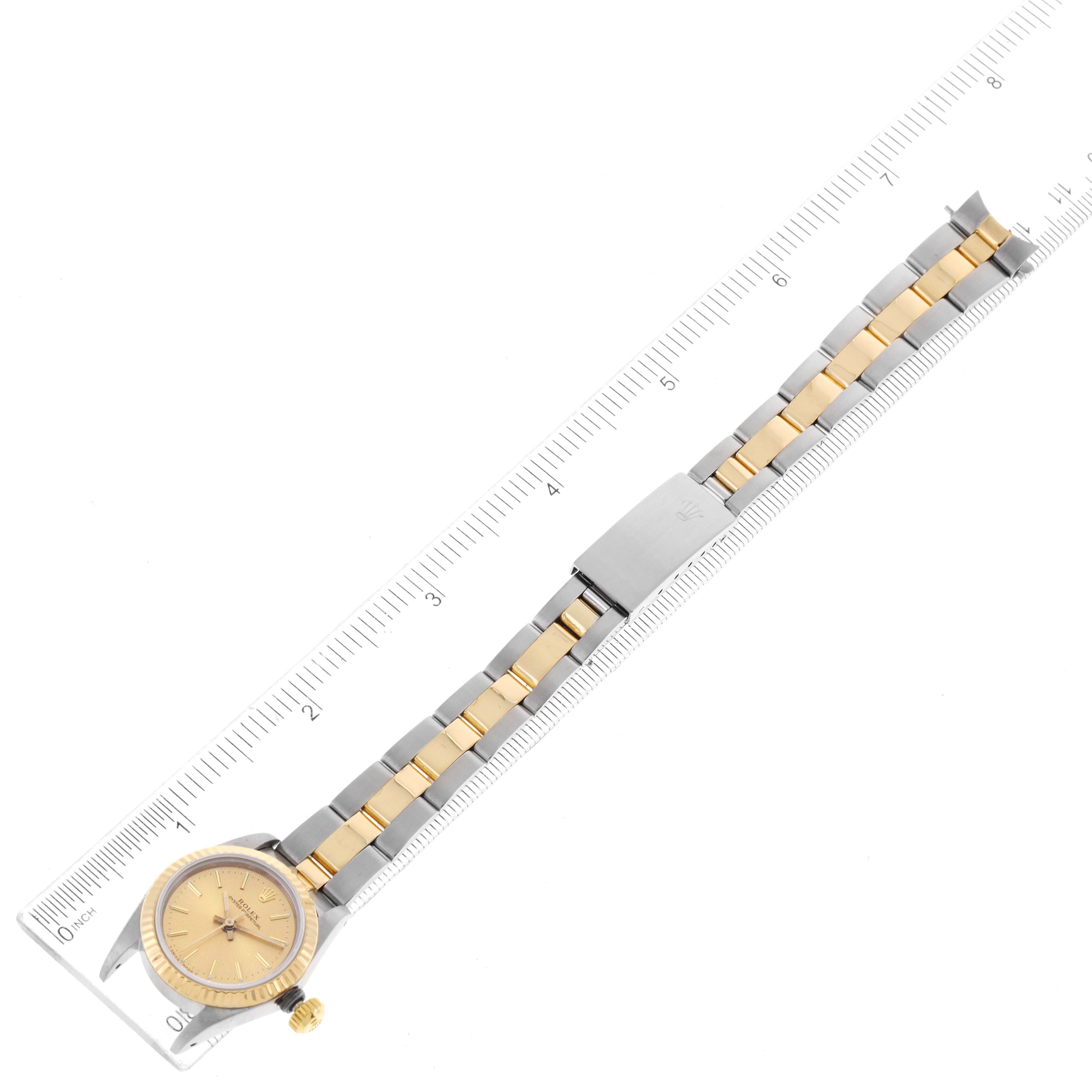 The image shows an overhead view of a Rolex Oyster Perpetual 67193 Women
s Steel and Gold (two tone) Champagne Dial 67193 Women
s Steel and Gold (two tone) Champagne Dial watch with a two-tone bracelet and a millimeter ruler for scale.