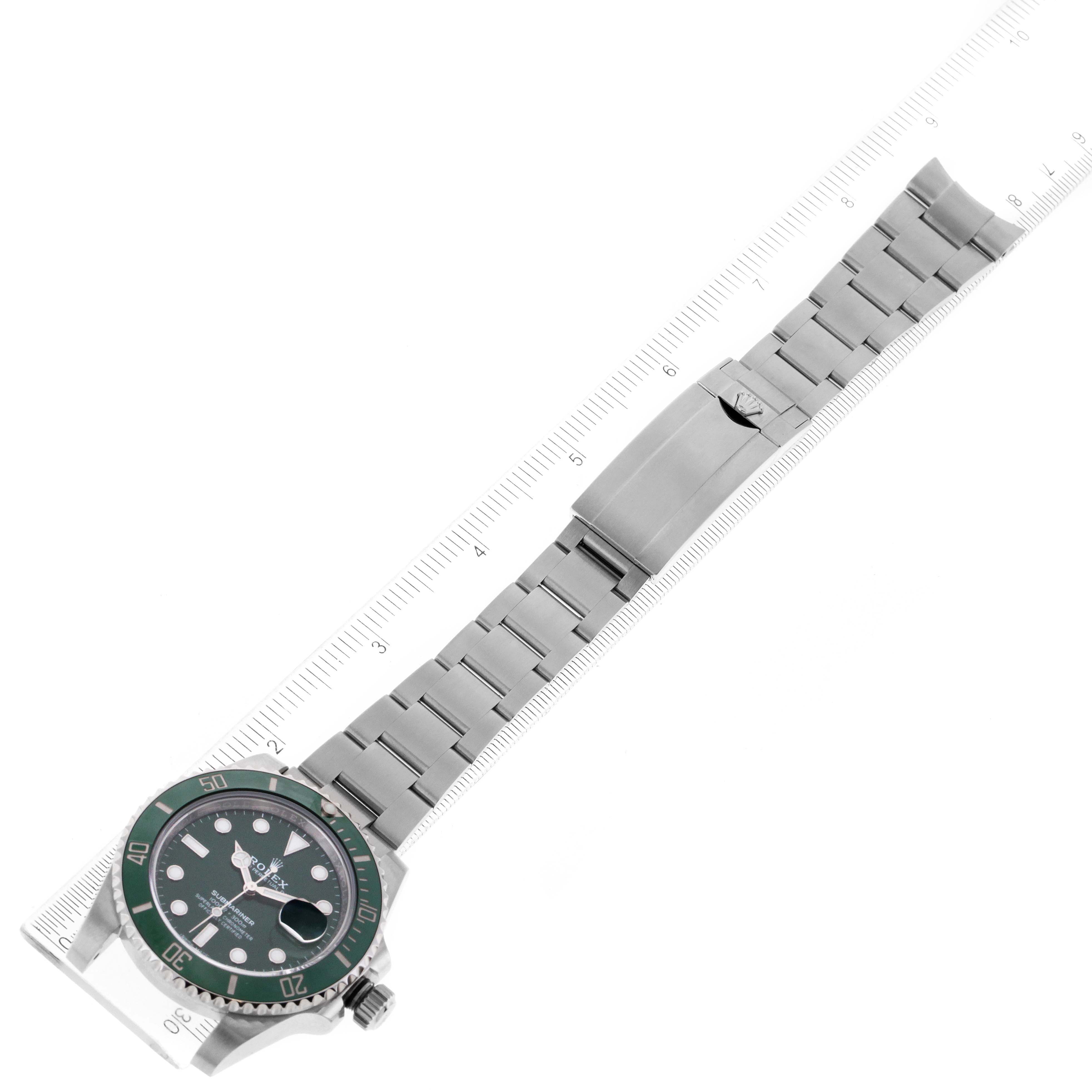 The image shows a top view of a Rolex Submariner 116610LV Men
s Stainless Steel Green Dial 116610LV Men
s Stainless Steel Green Dial watch, featuring the dial, bezel, and bracelet with a clasp, placed alongside a ruler.