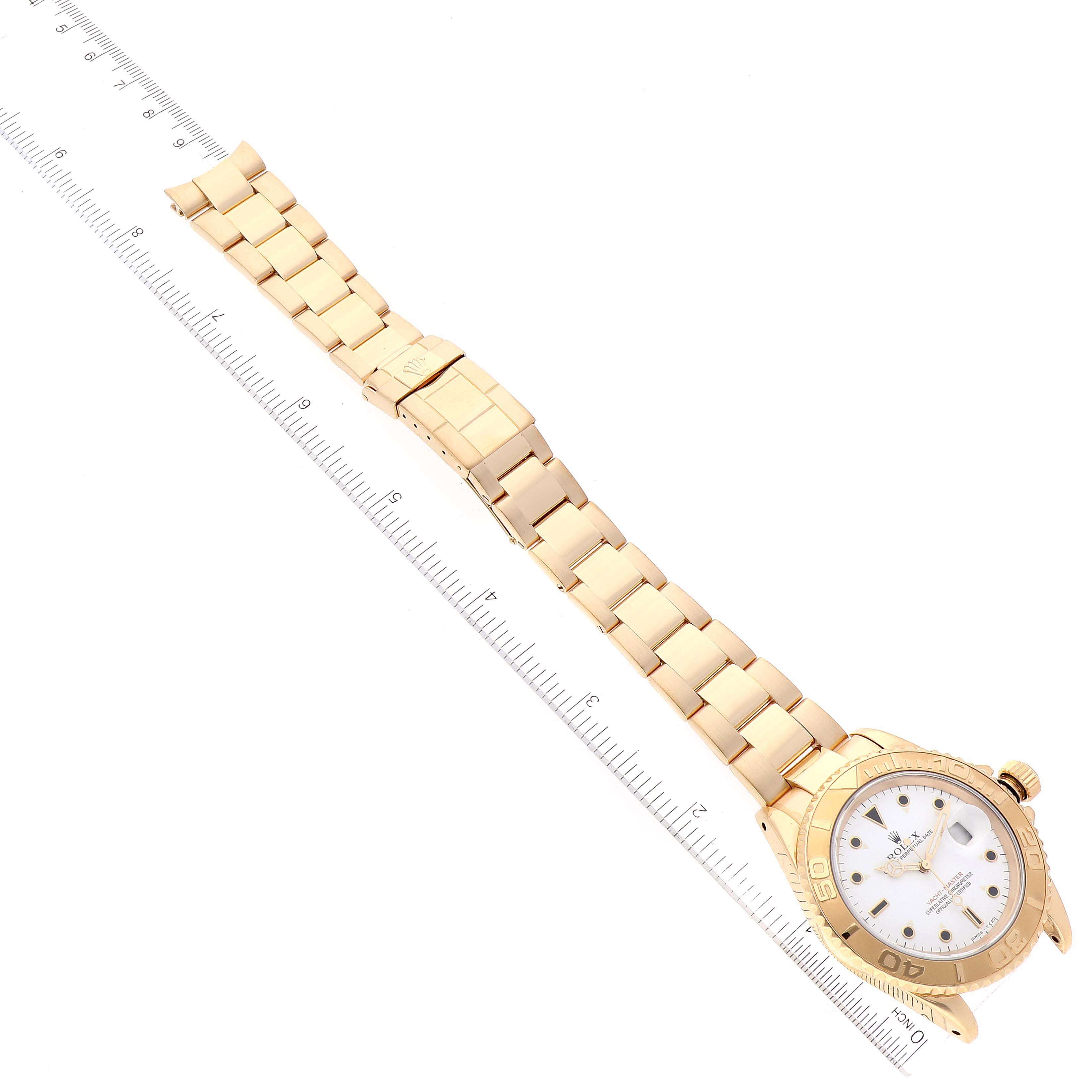 The image shows a Rolex Yacht-Master 16628 Men's Yellow Gold White Dial 16628 Men's Yellow Gold White Dial watch laid flat with its gold bracelet fully extended, alongside a ruler for scale.