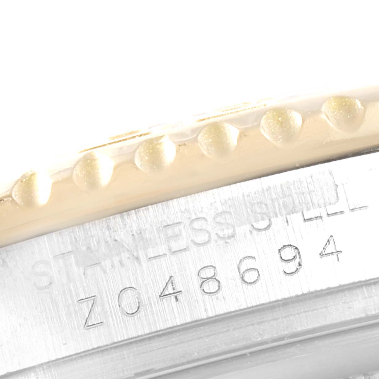 The image shows a close-up of the bezel and case side of a Rolex Yacht-Master 16623  Men
s Steel and Gold (two tone) White Dial 16623  Men
s Steel and Gold (two tone) White Dial watch, featuring the serial number and "Stainless Steel" engraving.