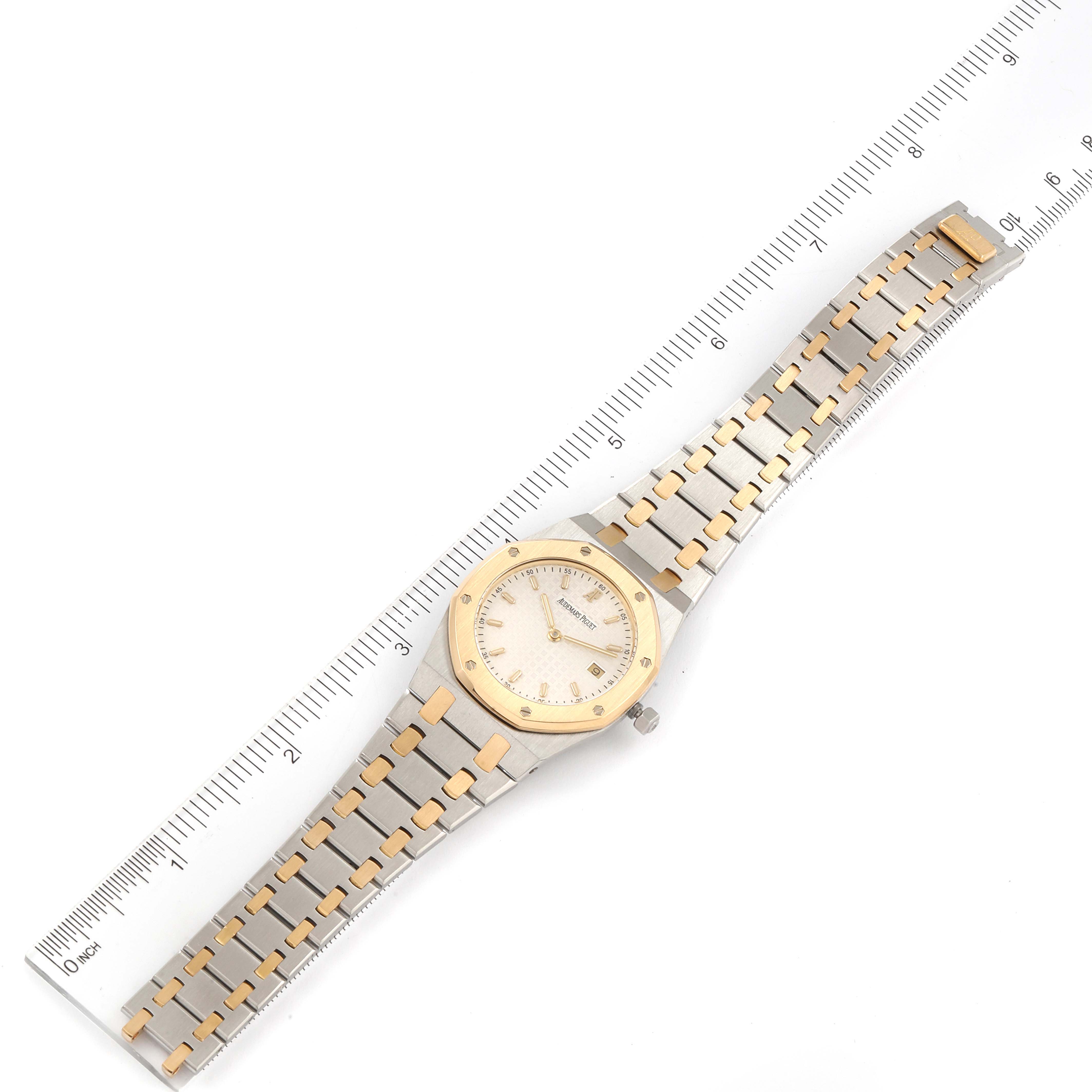 The Audemars Piguet Royal Oak 56175SA.OO.0789SA.09 Men's Steel and Gold (two tone) Silver Dial 56175SA.OO.0789SA.09 Men's Steel and Gold (two tone) Silver Dial watch is shown in a top-down view, displaying the face, bezel, and metal bracelet alongside a ruler for scale.