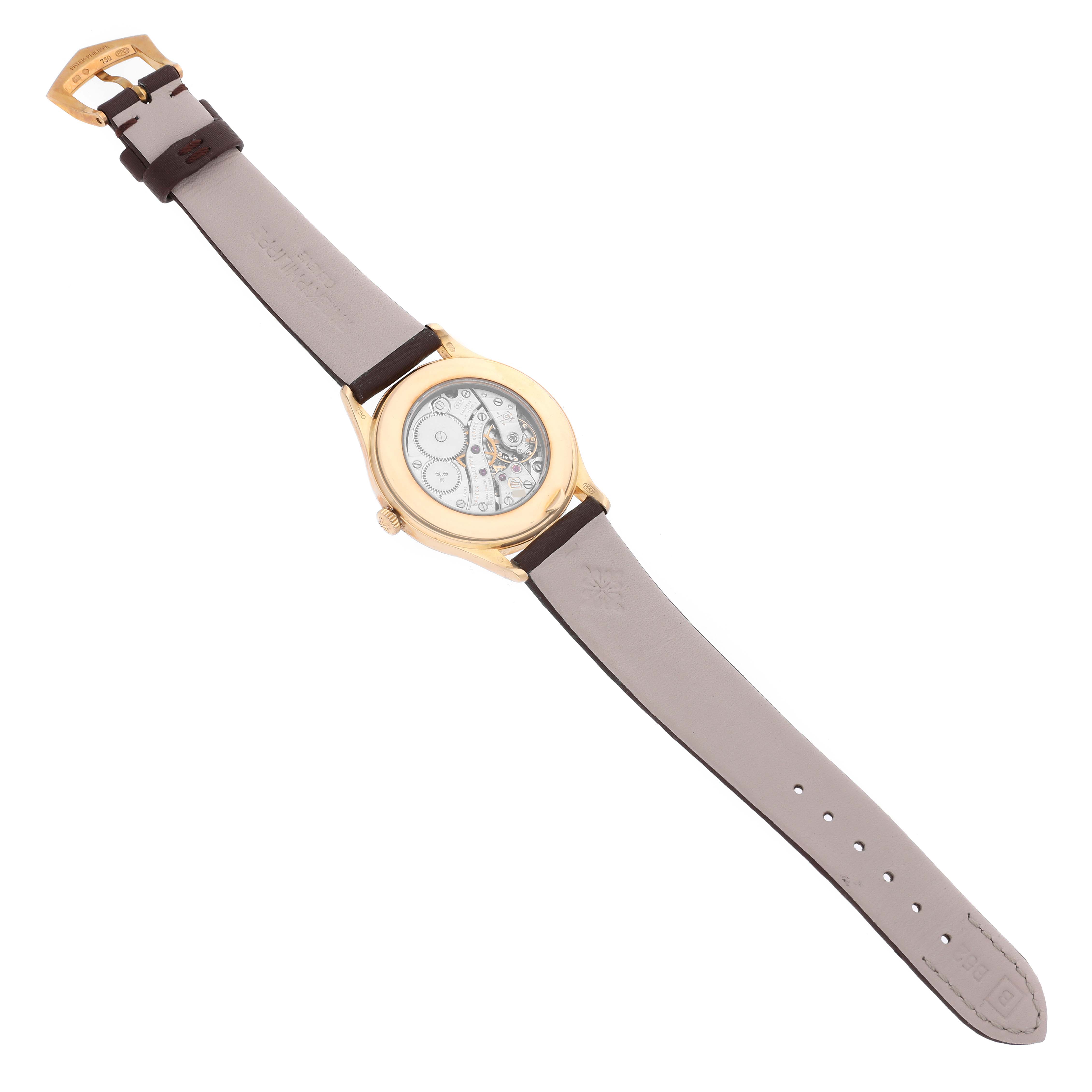 The Patek Philippe Calatrava 4897R-001 Womens Rose Gold Brown Dial watch is shown from a top-down angle, highlighting its gold case, intricate mechanism, and leather strap.