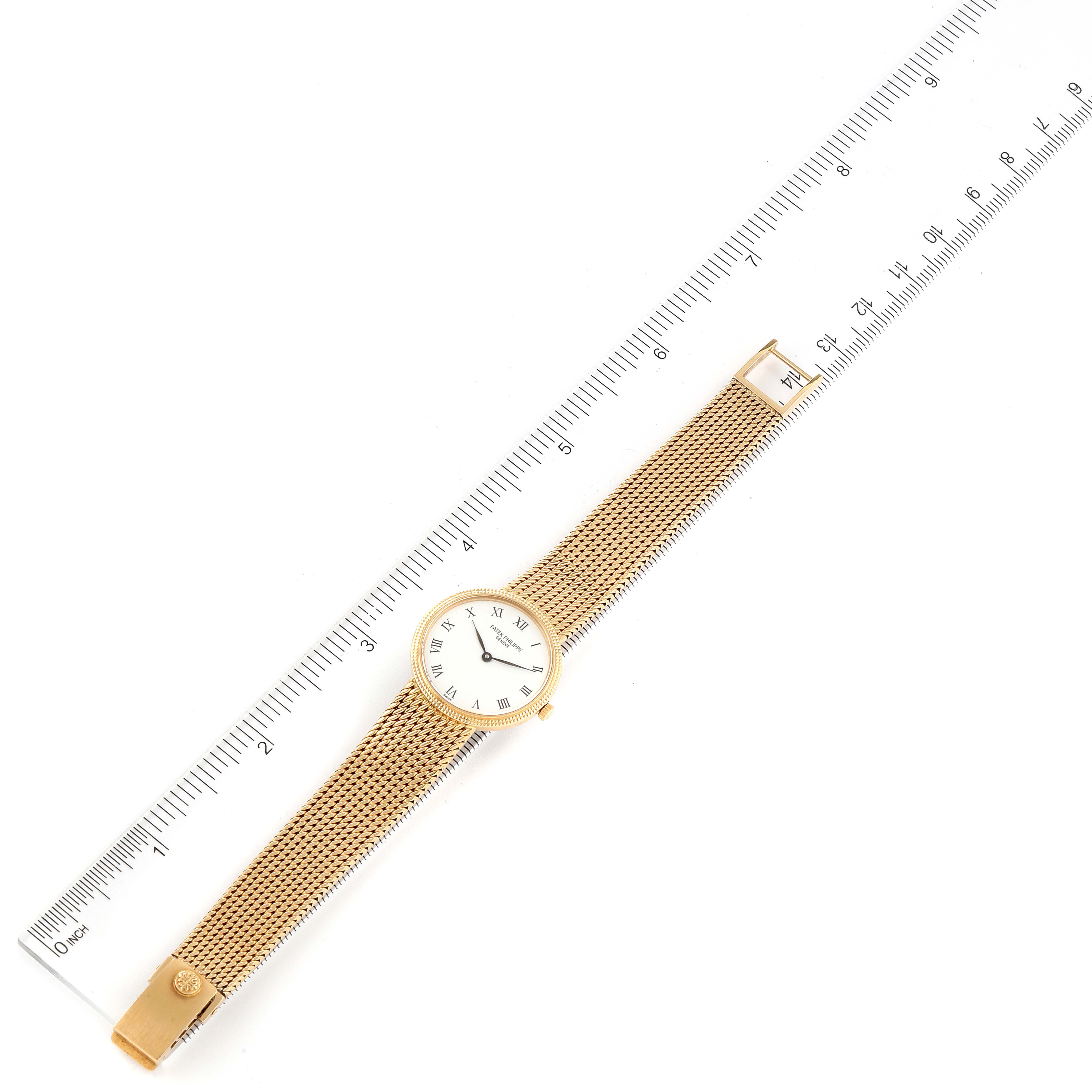 The Patek Philippe Calatrava 4819 Women's Yellow Gold White Dial 4819 Women's Yellow Gold White Dial watch is displayed flat with its gold mesh band and face visible, beside a ruler for size reference.