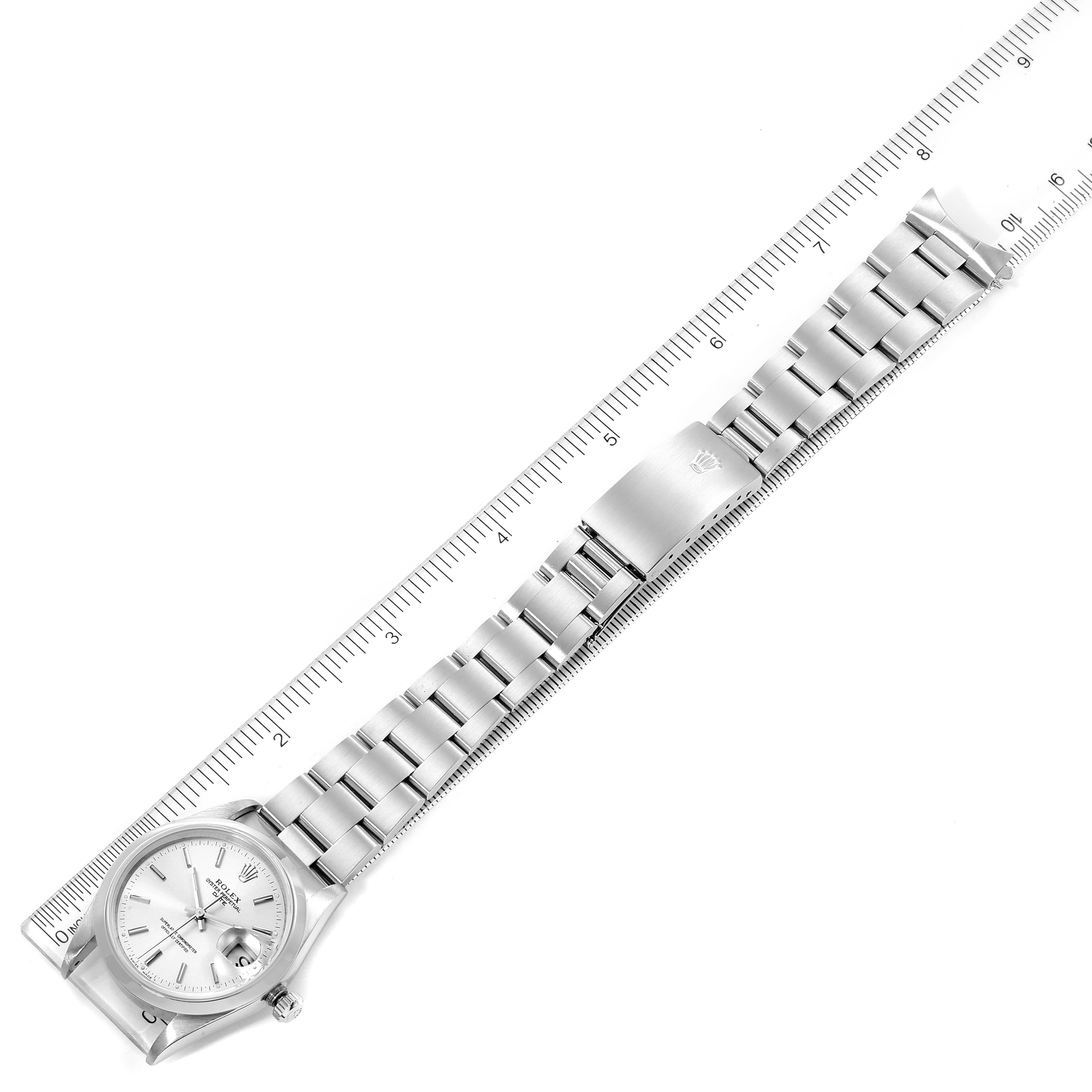The image shows an overhead view of a Rolex Date 15200 Men's Stainless Steel Silver Dial 15200 Men's Stainless Steel Silver Dial watch, including its dial, bracelet, and clasp, alongside a ruler for scale.