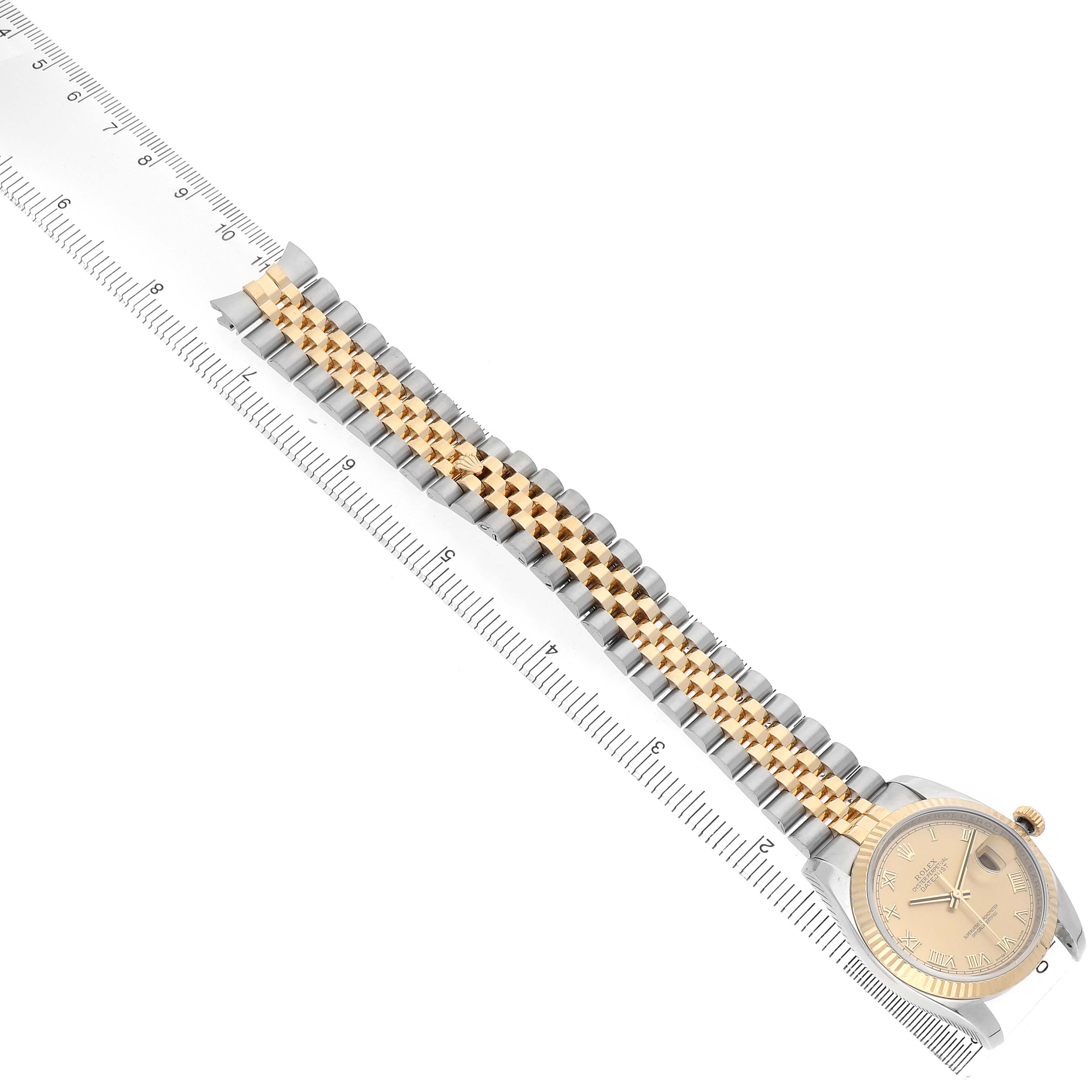 The Rolex Datejust 116233 Men's Stainless Steel Champagne Dial watch is shown from a side angle, displaying the dial, bezel, and the Jubilee bracelet alongside a ruler.